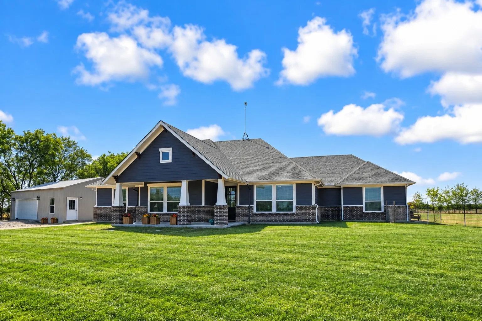 Modern home with dark siding, brick accents, and a covered entry