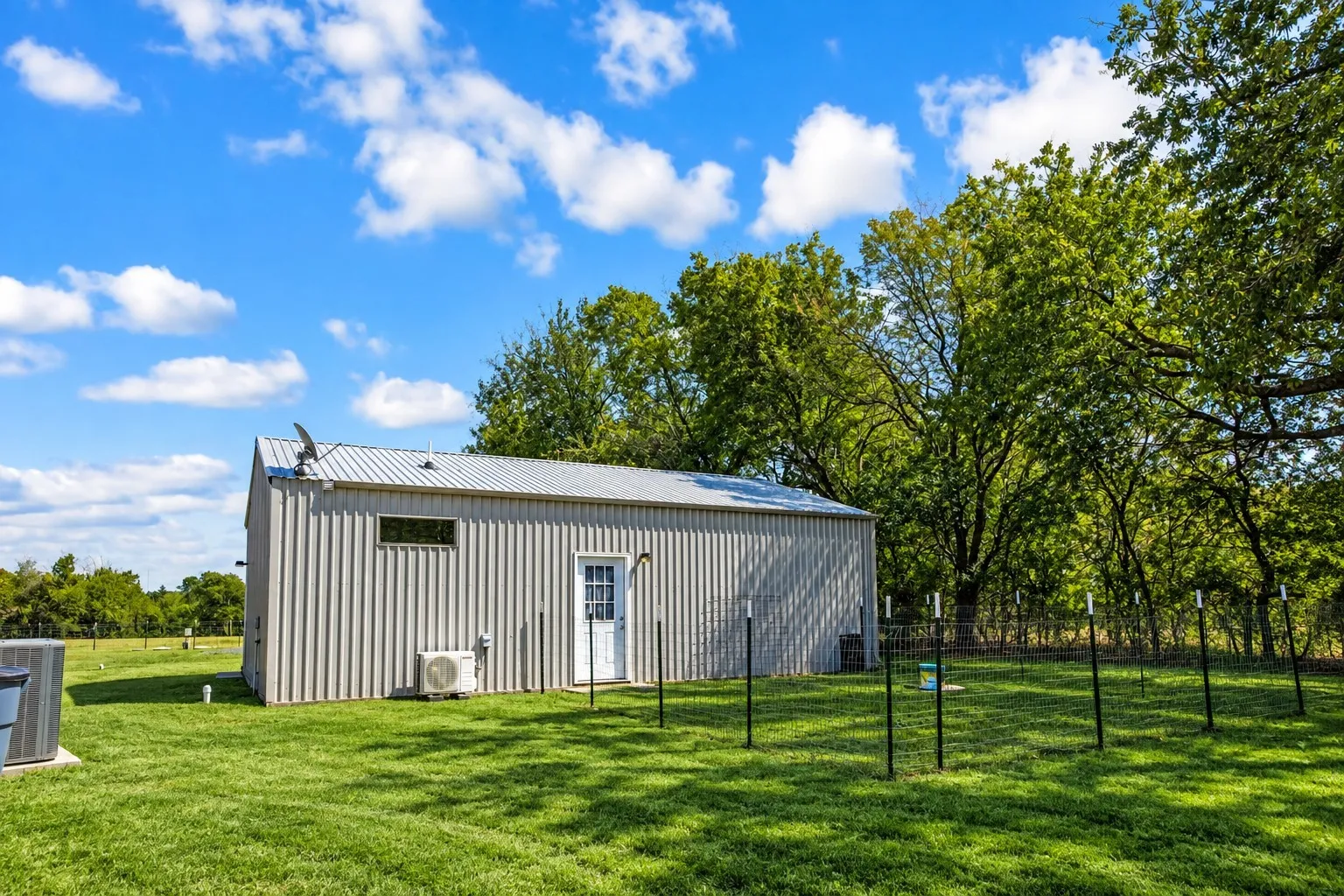 Metal-sided building with a white entry door, horizontal window, and metal roof