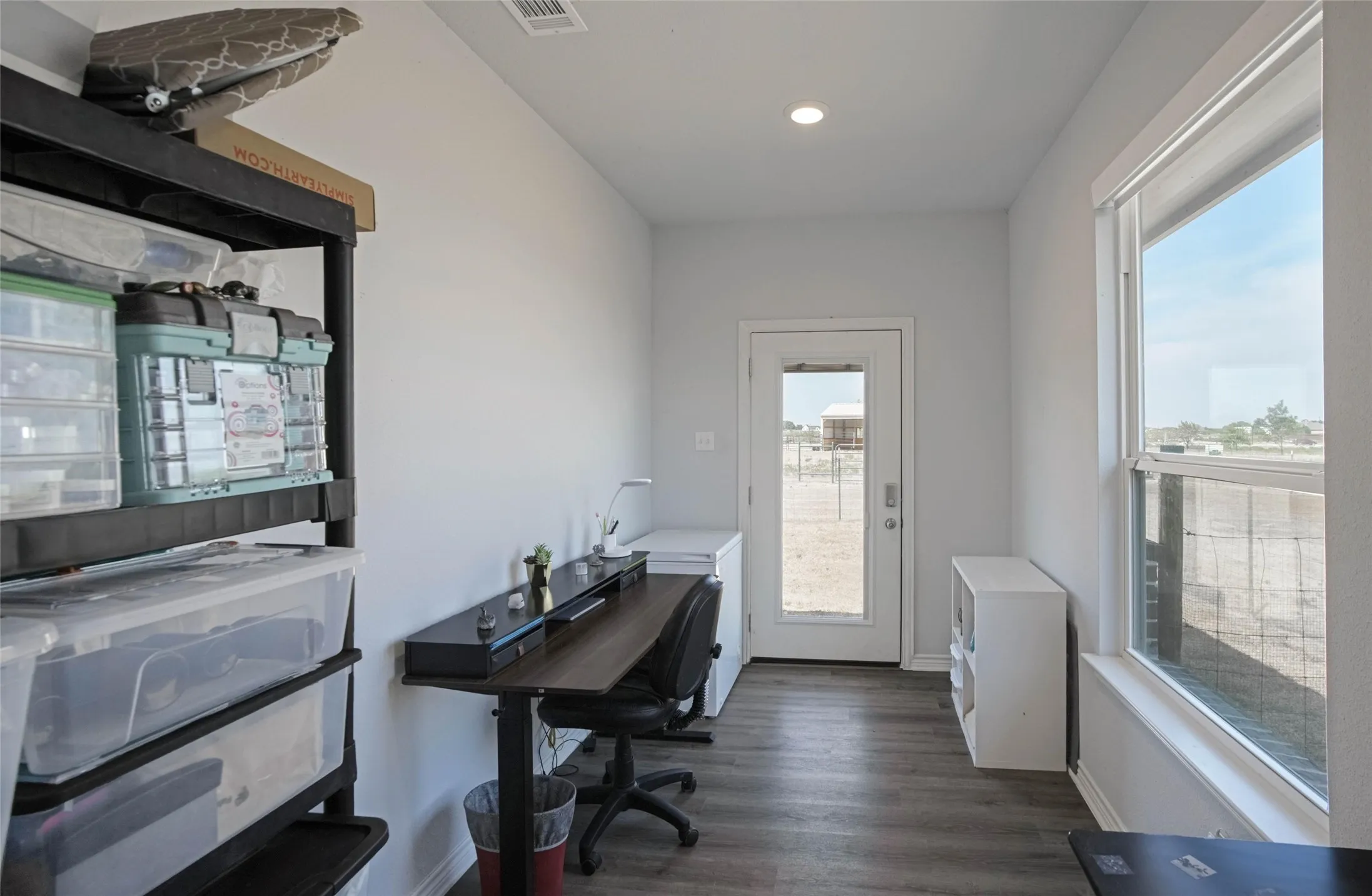 Recessed lighting, wood-finish flooring, white walls, large window, and a glass-paneled door