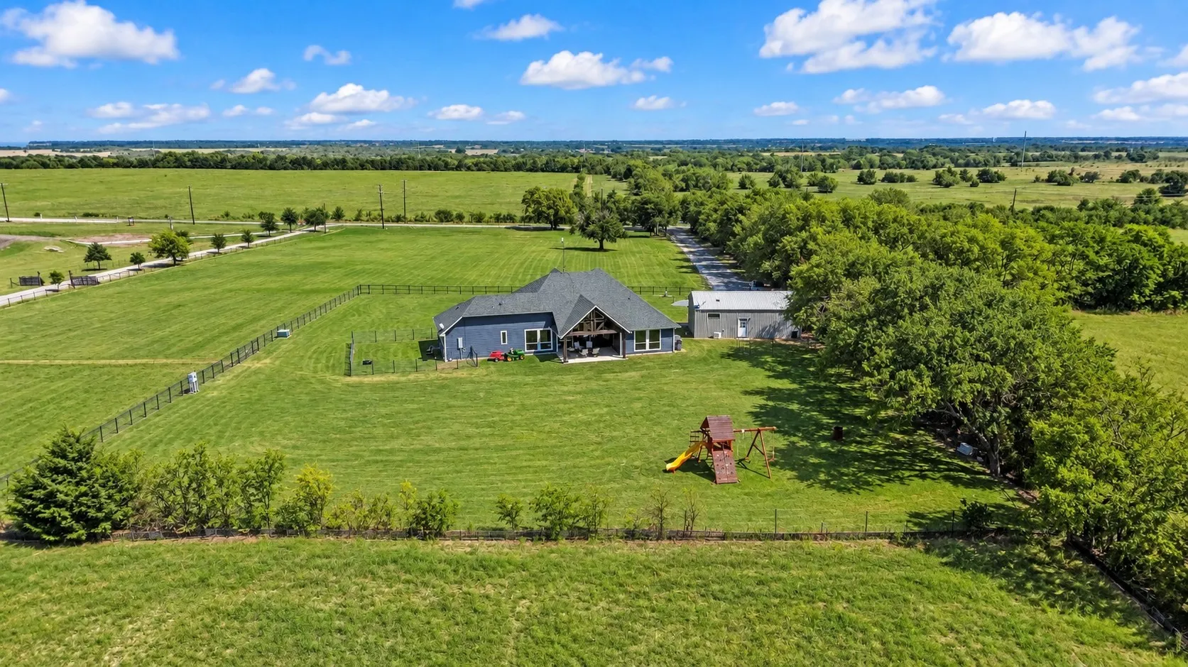 Expansive property featuring a single-story residence, a detached auxiliary building, and extensive green space