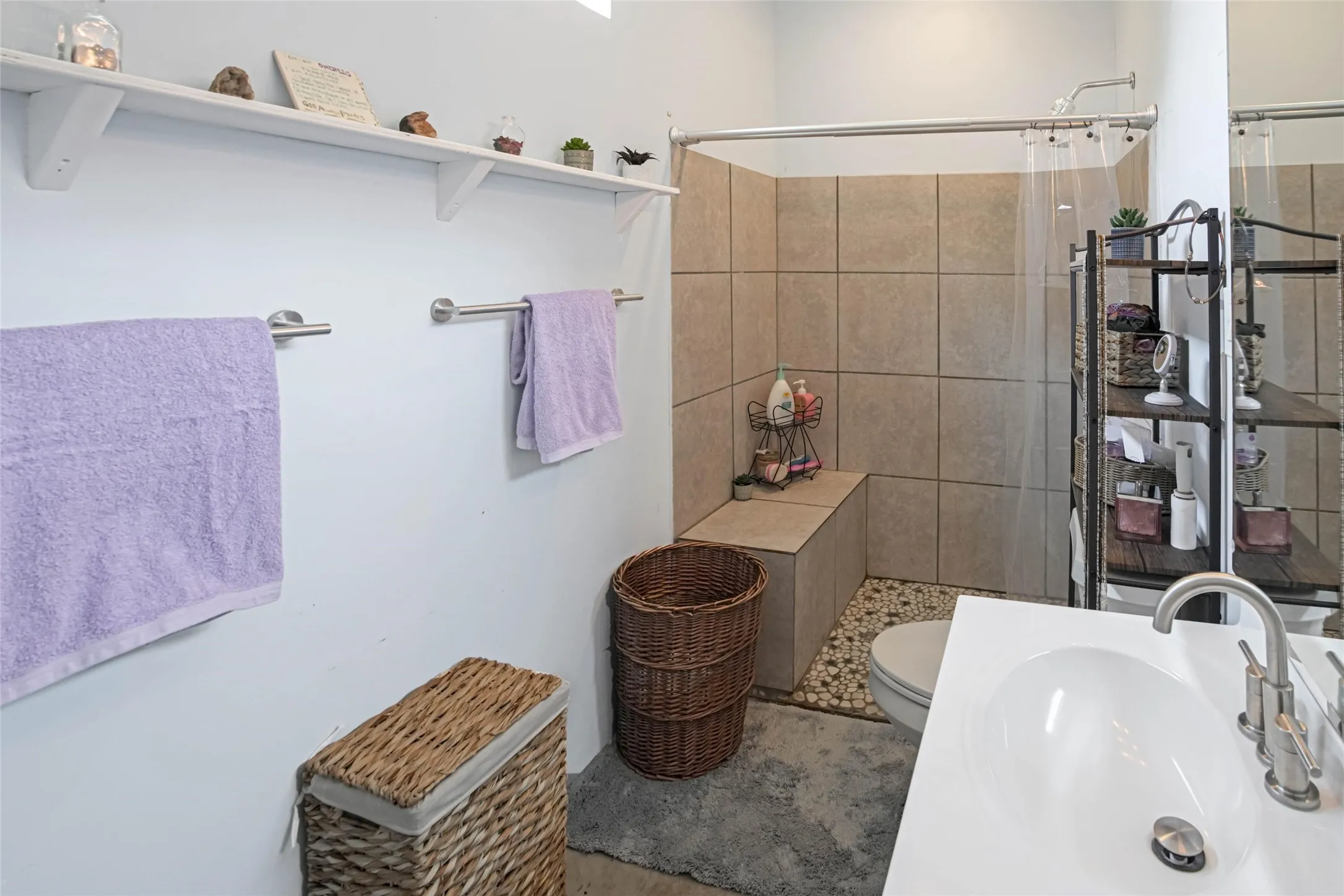 Bathroom featuring a walk-in shower with tiled walls, built-in shower bench, and river rock flooring