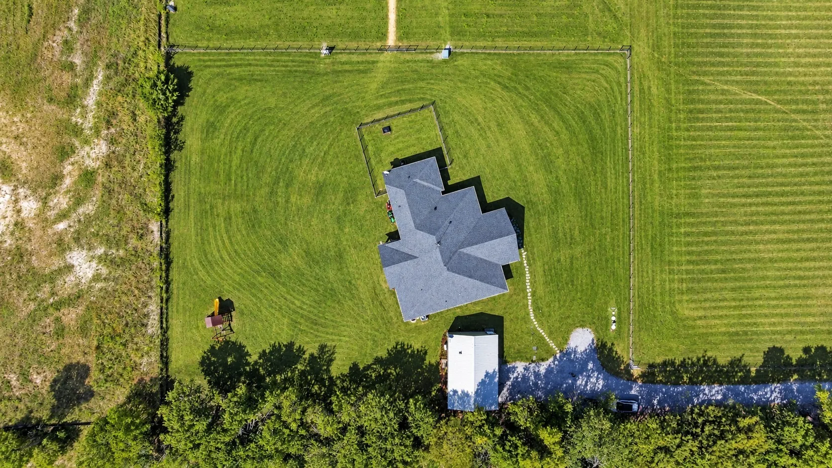 Spacious property featuring a main residence with a multi-gabled roof, an accessory building, and a gravel driveway
