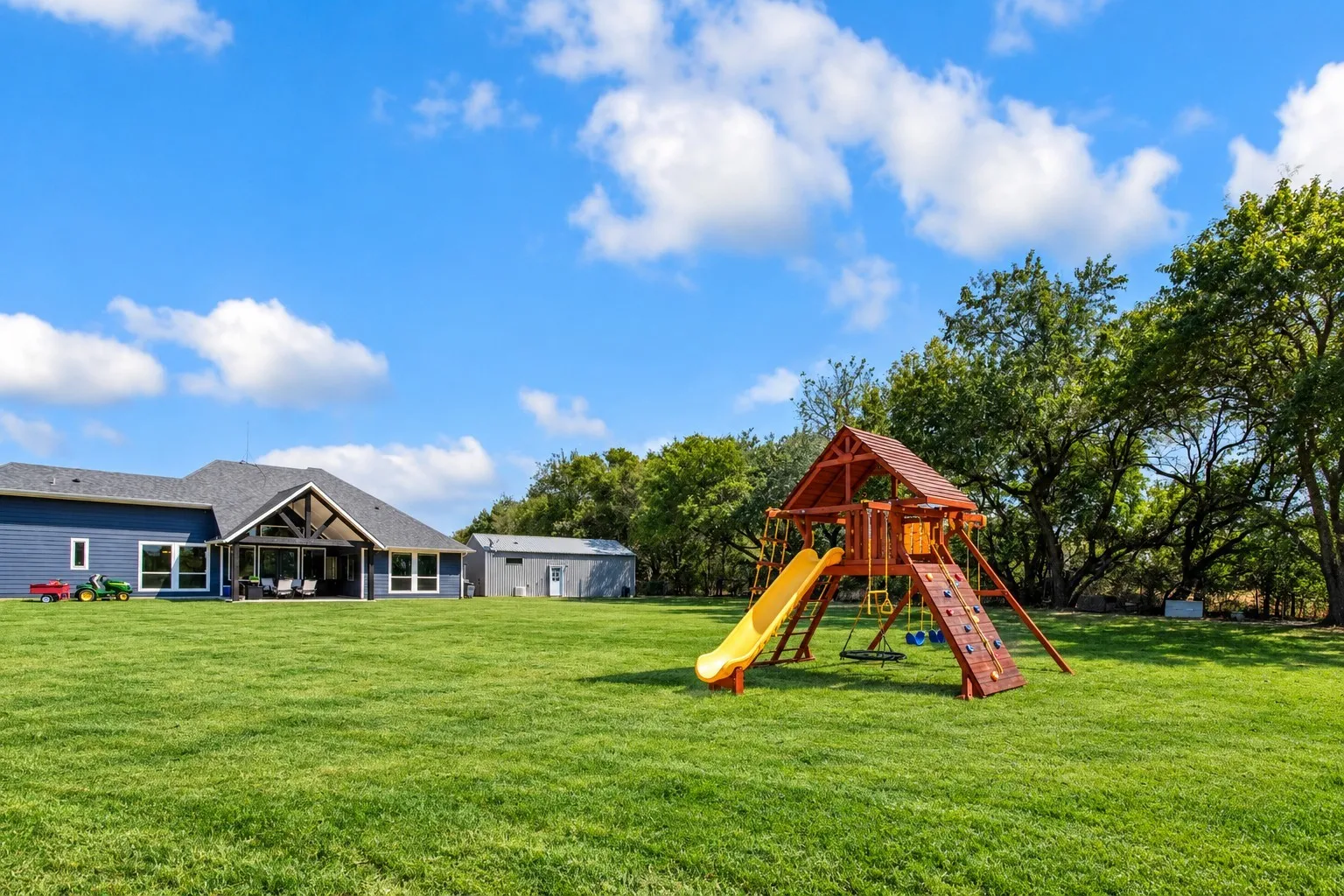 Expansive green lawn with mature trees and a detached structure