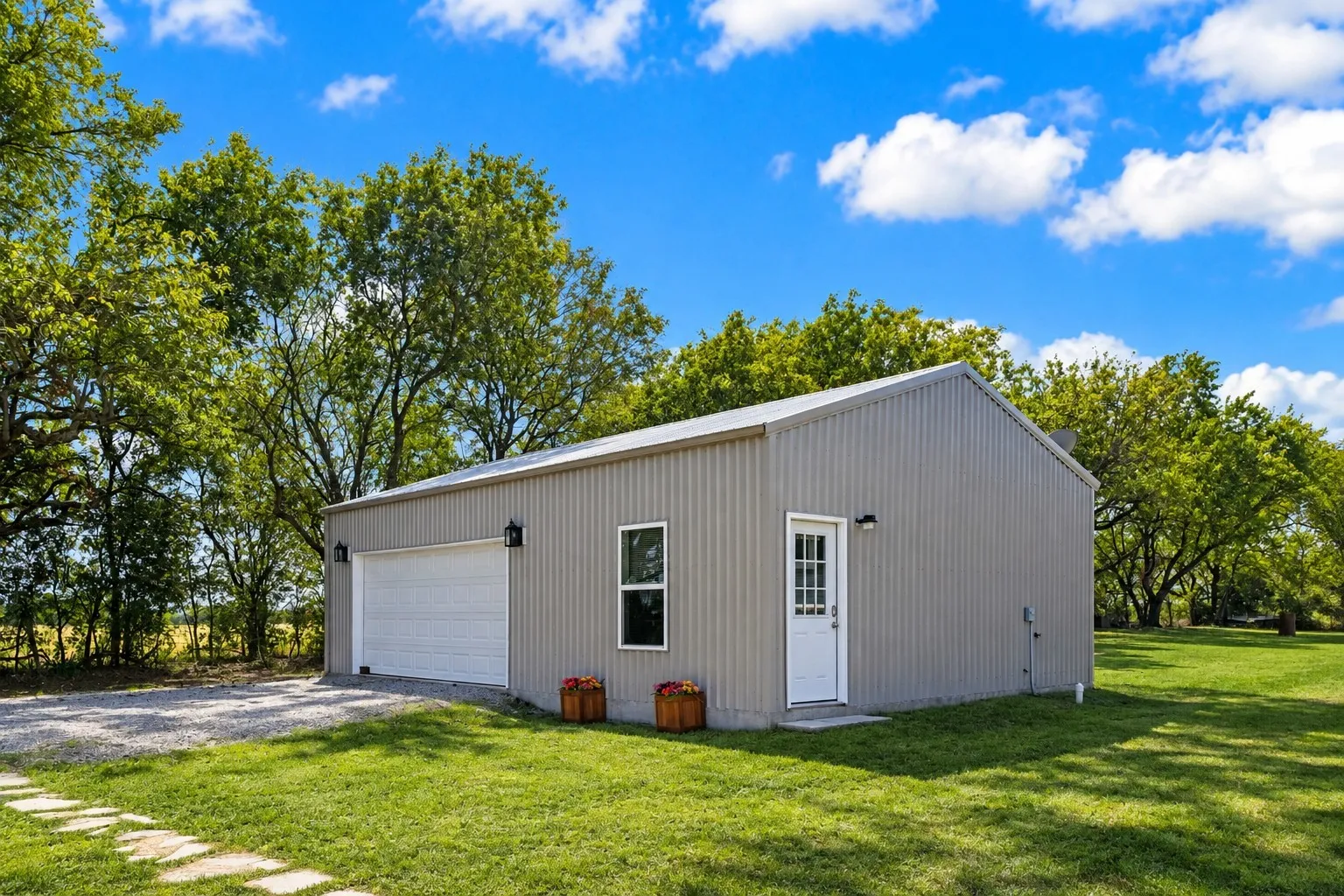 Corrugated metal exterior with a single garage door, a white entry door, and exterior lighting fixtures