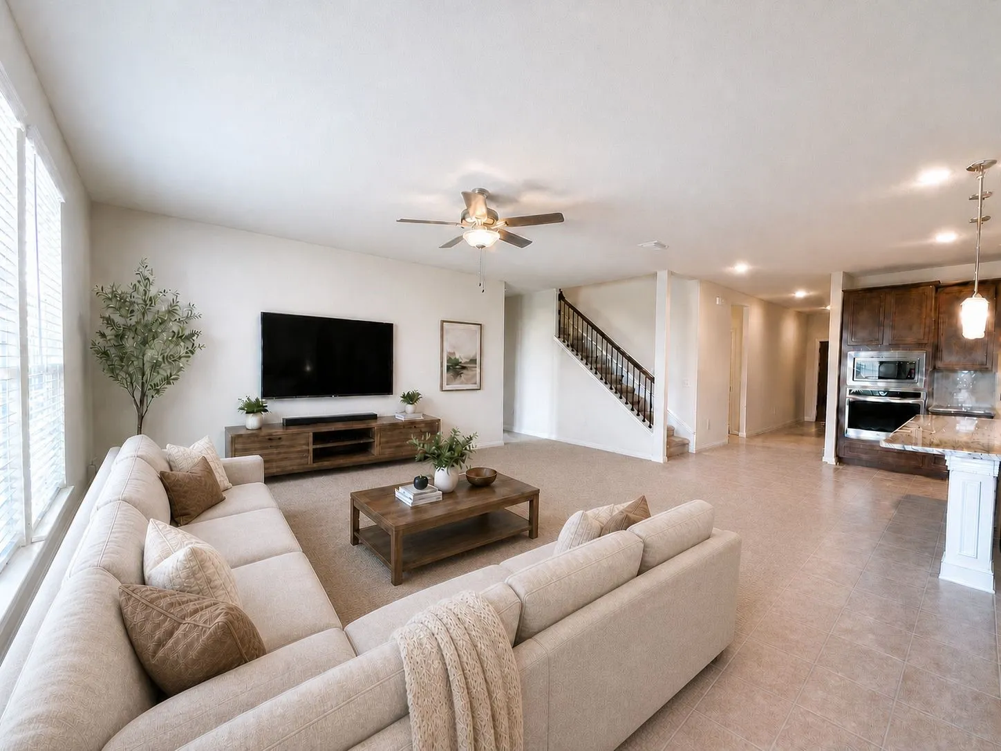 AI ENHANCED Open-concept living area featuring a neutral carpet, a ceiling fan with integrated lighting, and a white baluster staircase