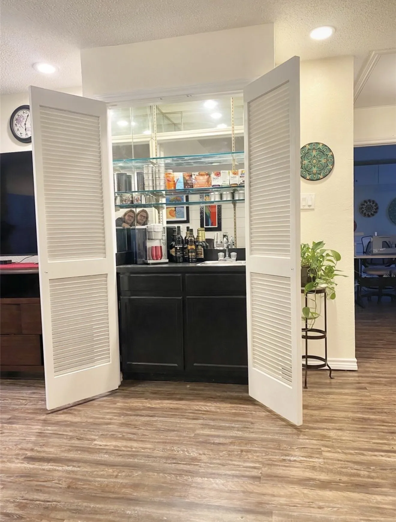 Built-in wet bar with dark cabinetry and  integrated sink and mirrored backsplash.