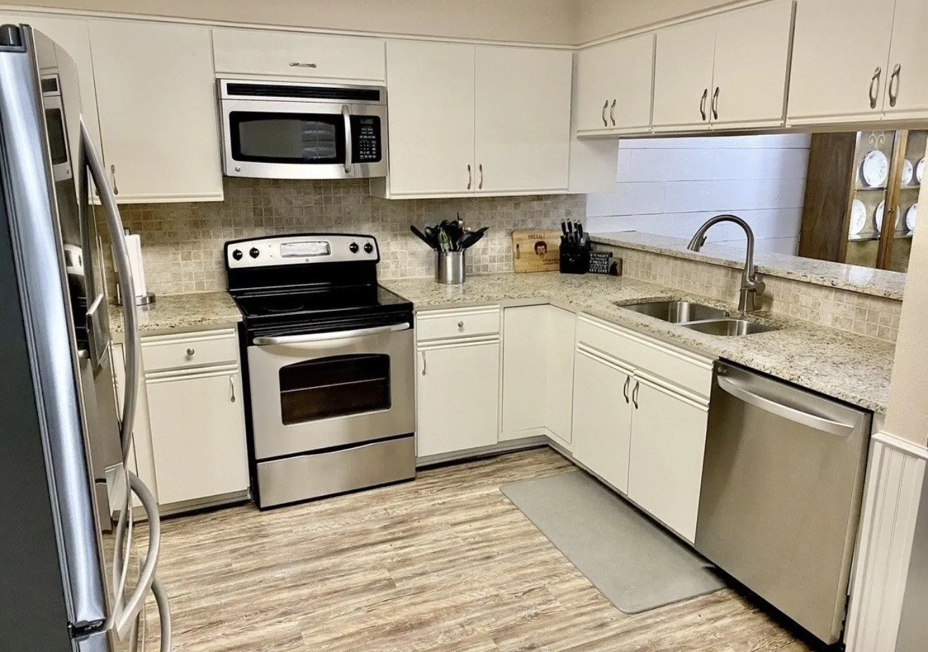 Kitchen featuring white cabinetry, wood-finish flooring, stainless steel appliances, and light-toned countertops