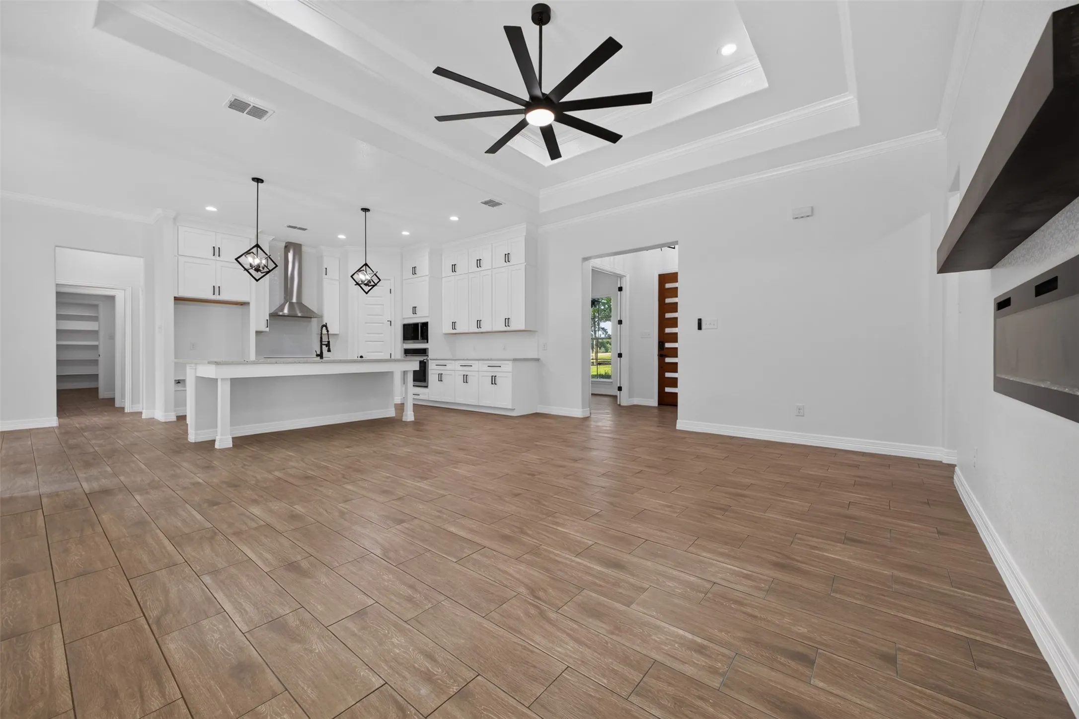 Spacious open-concept living area with a tray ceiling, statement ceiling fan, and seamless flow into the kitchen.
