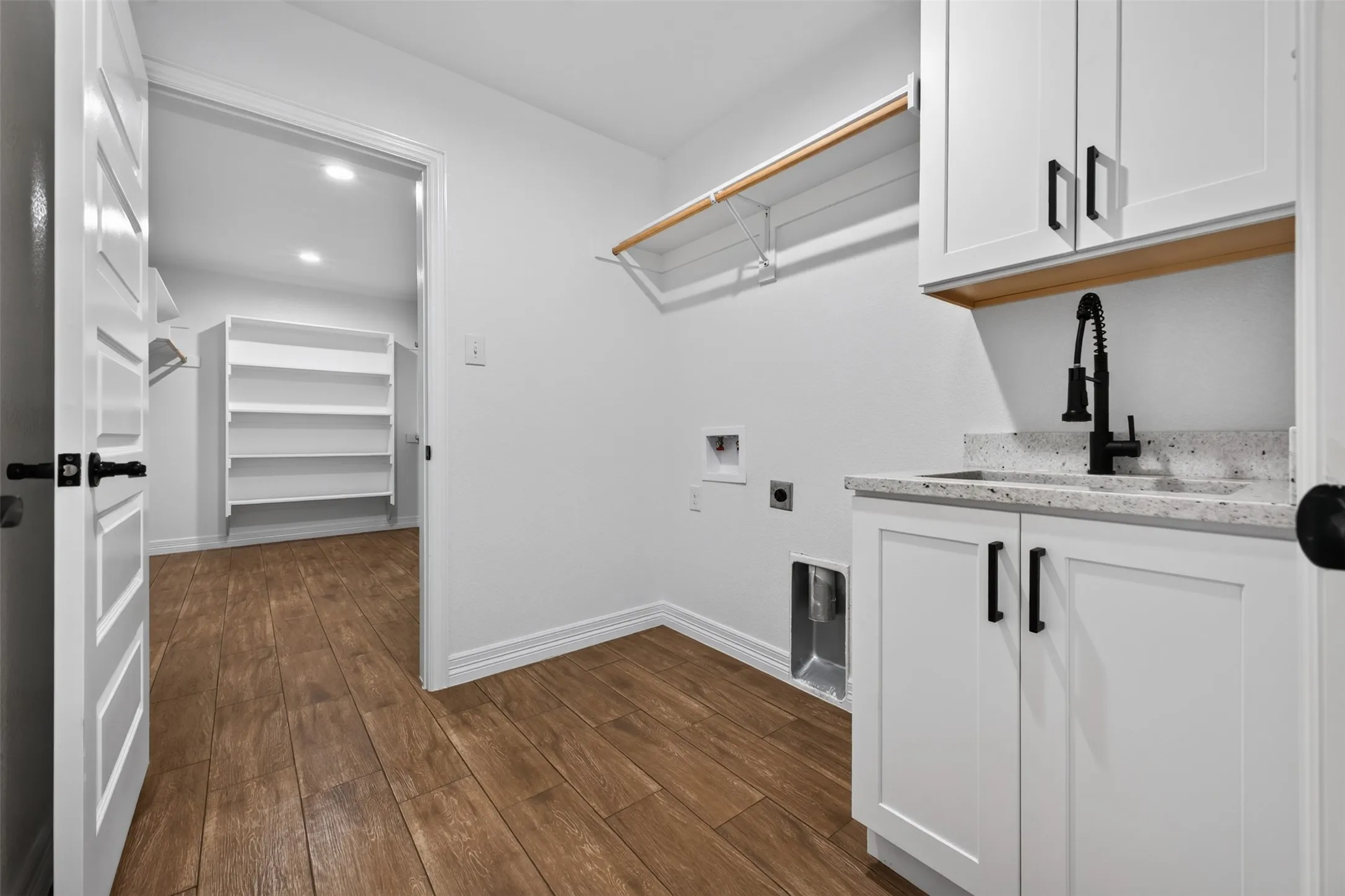 Roomy laundry room with built-in cabinetry, utility sink, hanging space, and additional storage for everyday organization.  Access directly to primary walk-in closet.