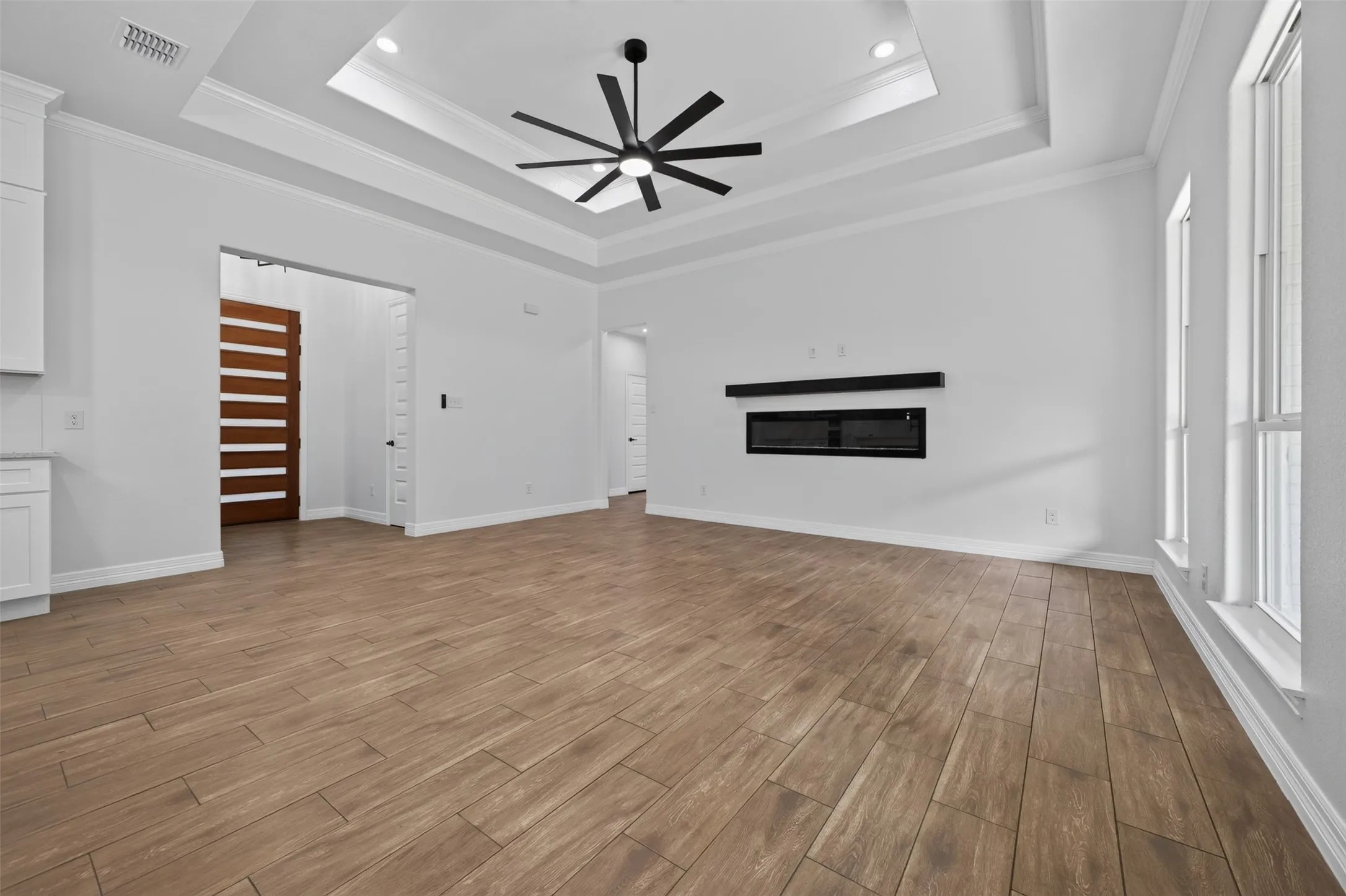 Living room features a sleek modern fireplace, dramatic tray ceiling, and abundant natural light