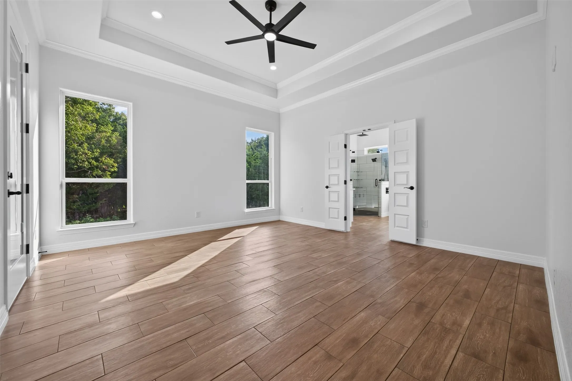 Expansive primary suite with abundant natural light, elevated ceiling detail, and convenient access to the private ensuite bath.