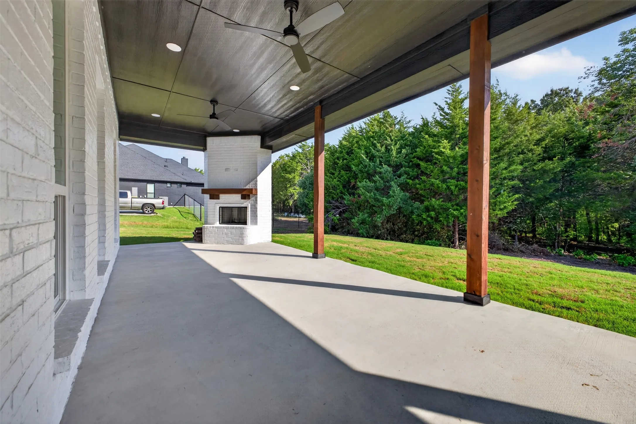 Expansive covered patio with outdoor fireplace and ceiling fans-an ideal space for outdoor living and entertaining.