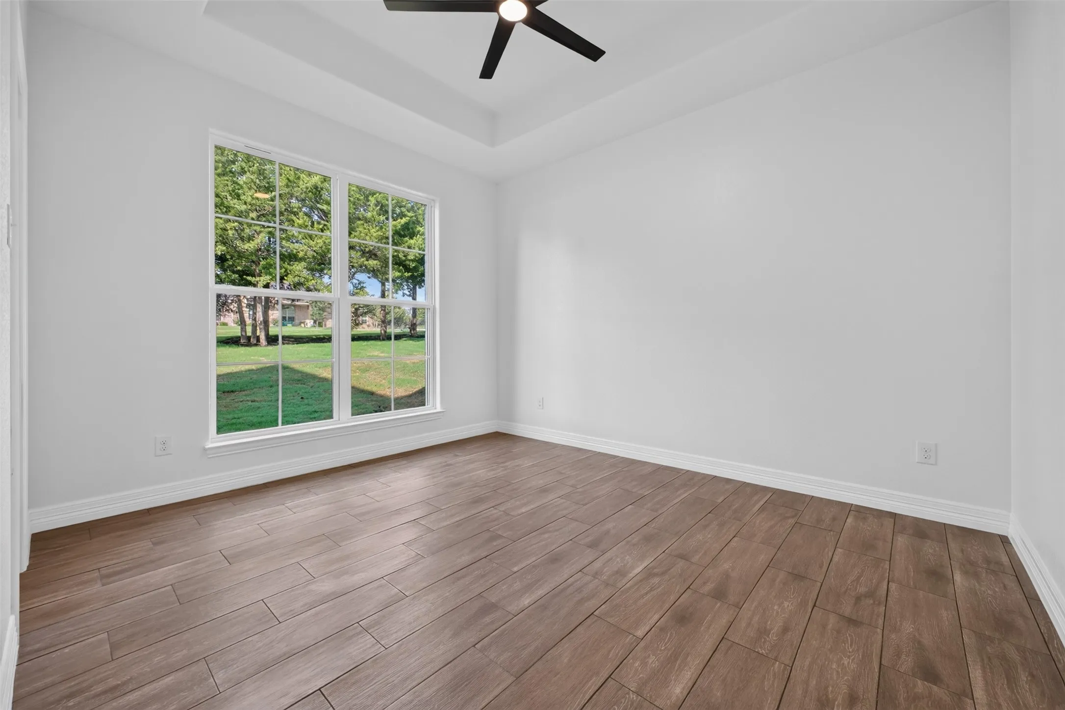 Spacious front bedroom featuring a tray ceiling, abundant natural light and a large walk-in closet, with direct access to Jack-and-Jill en-suite