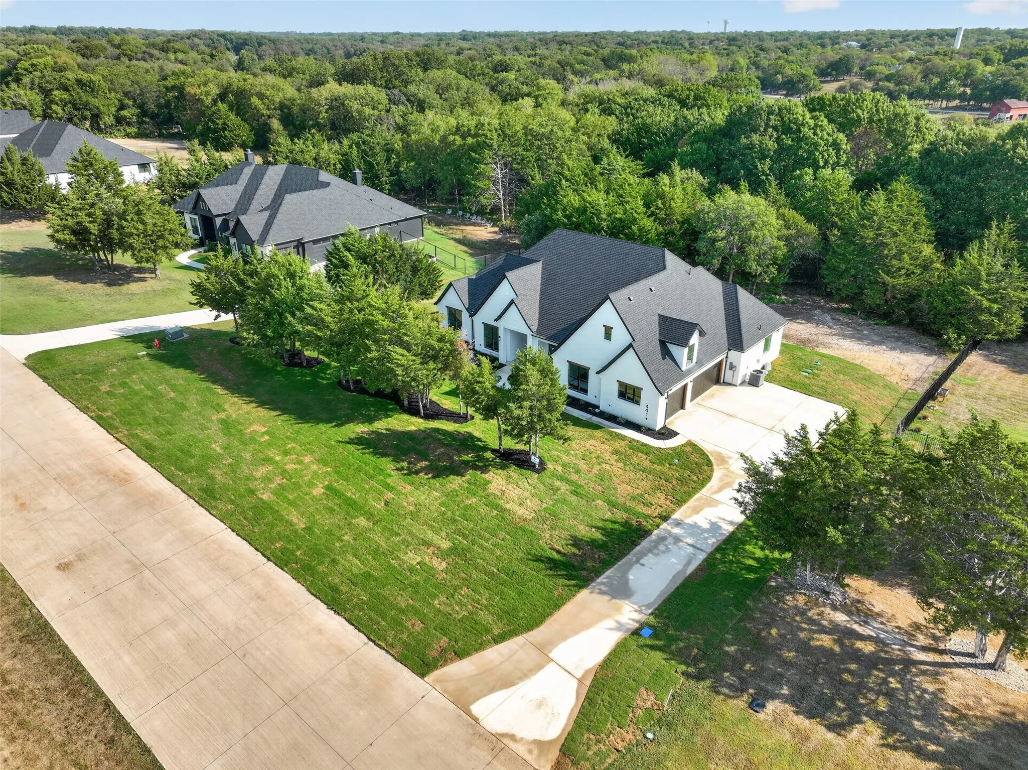 Aerial view showcasing the home's spacious setting, mature trees, and beautiful surrounding landscape.