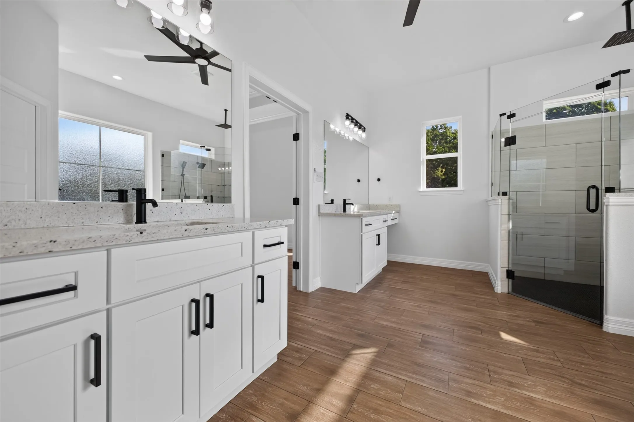 Spacious primary bath with separate vanities, generous counter space, abundant storage, and oversized glass-enclosed walk-in shower.