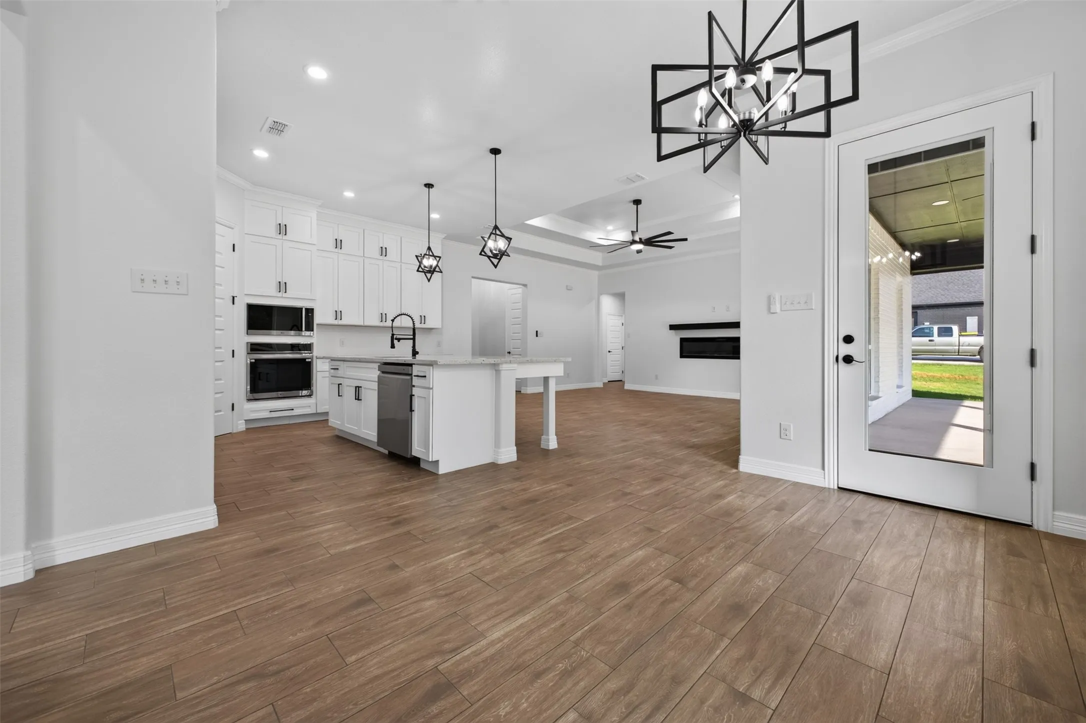 Open-concept kitchen and dining area with statement lighting and seamless flow to the living room and covered outdoor living space.