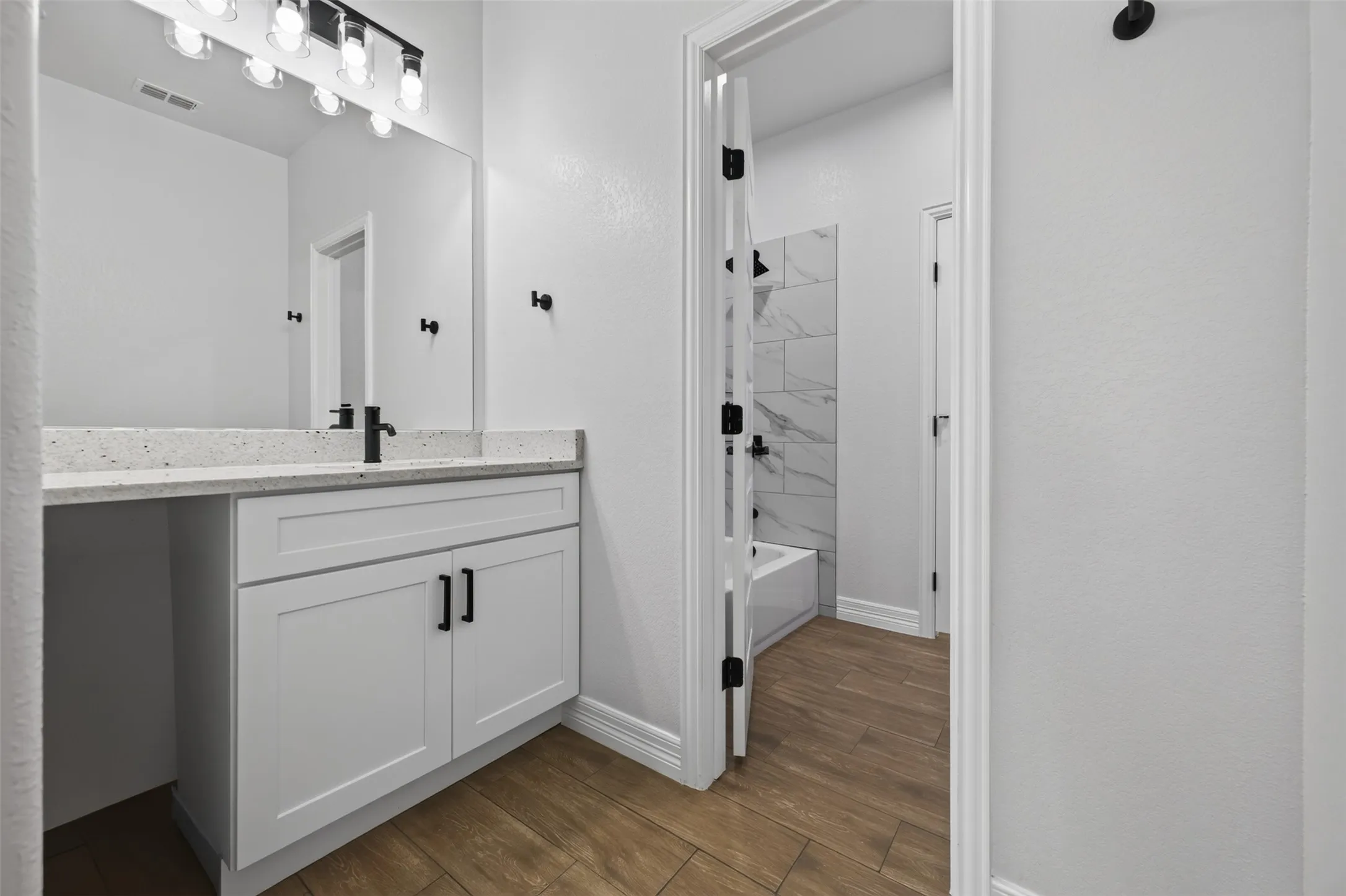 Jack-and-Jill bath featuring a private vanity area with direct access to shared tub and shower area.