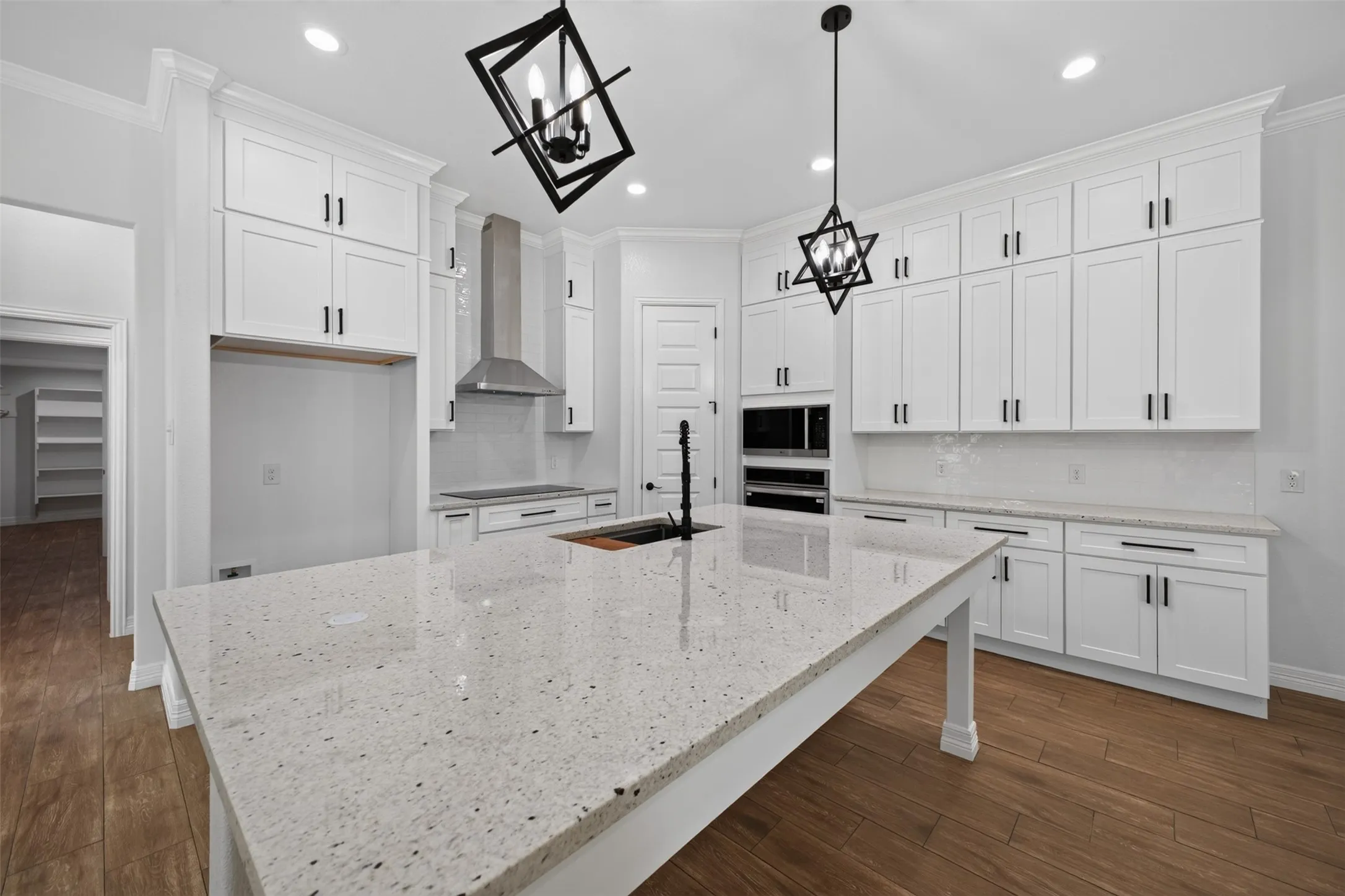 Beautifully designed kitchen featuring an oversized island, abundant cabinetry, built-in appliances, and stylish statement lighting.