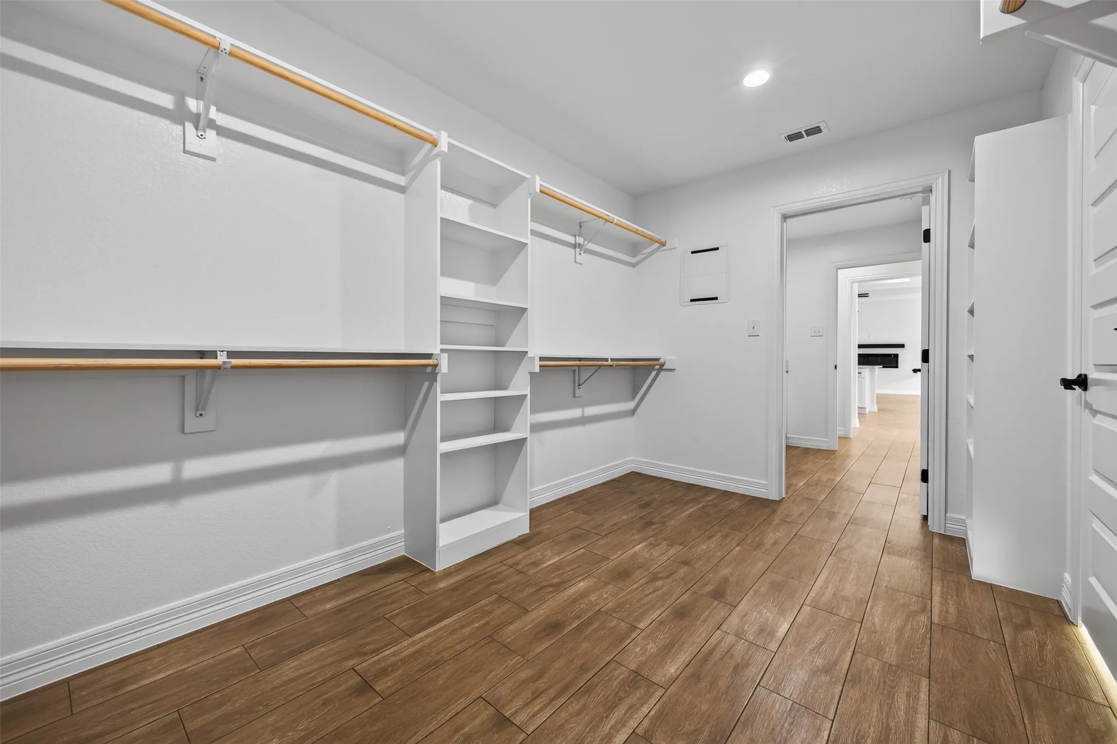 Spacious primary walk-in closet with abundant hanging space, built in shelving, and plenty of room for organized storage.  Access directly to the laundry area.
