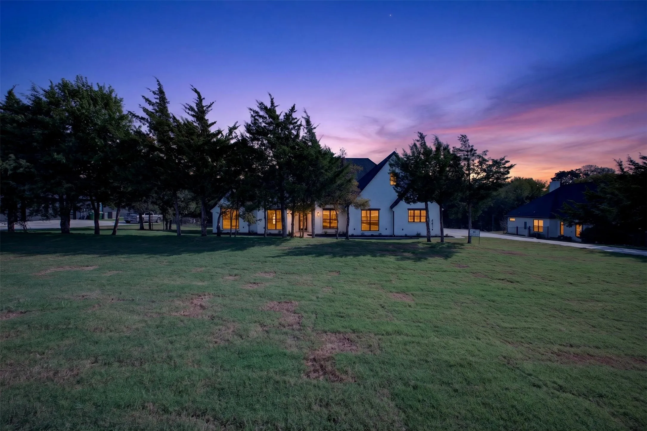 Beautiful twilight view showcasing the home's inviting exterior, matured trees and expansive yard.