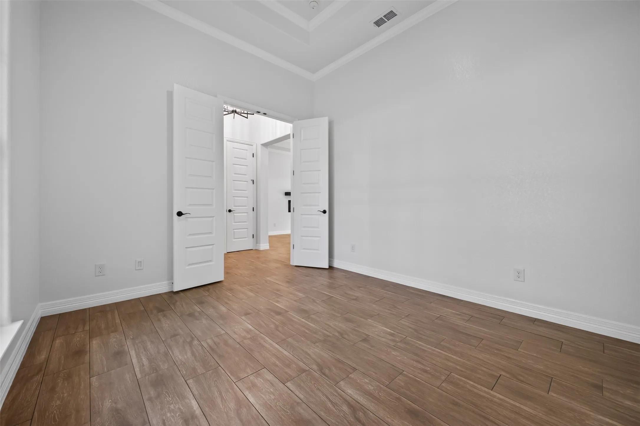 Generously sized home office with elevated ceiling details and plenty of space for a substantial workspace or additional seating.