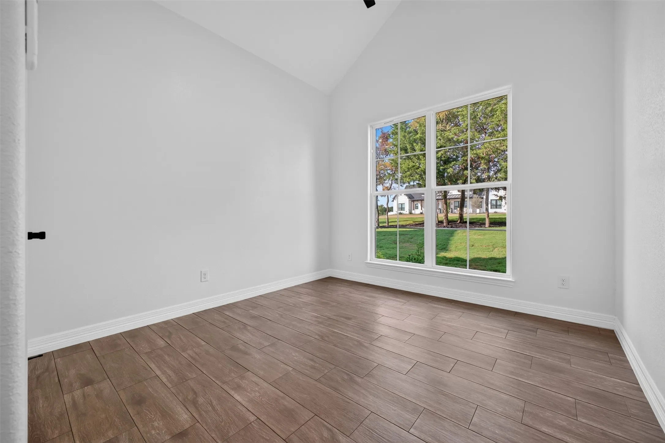 Front bedroom with abundant natural light and spacious walk in closet, features vaulted ceiling.