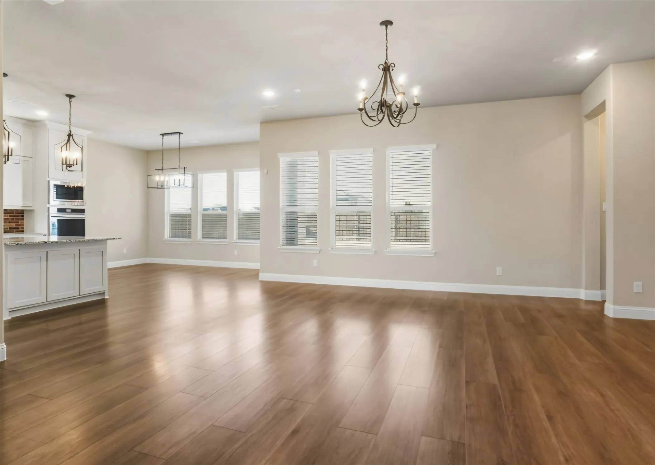 Expansive open-concept living area featuring wood-finish flooring, recessed lighting, and multiple windows