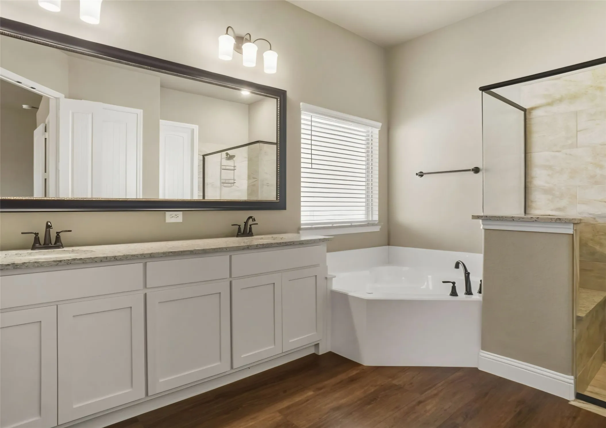 Dual vanity with light cabinetry, stone-finish countertop, and dark-finish faucets