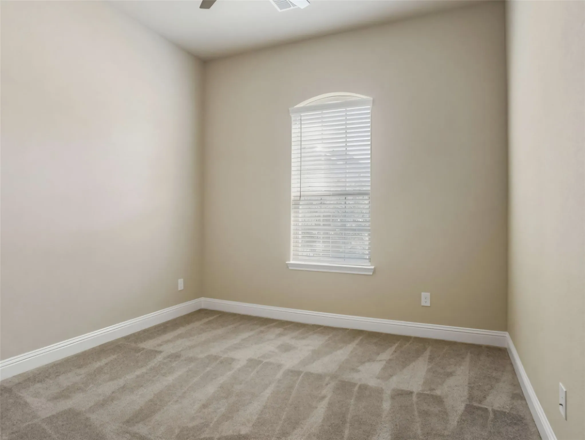 Arched window with blinds, neutral tone walls, white trim, and carpeted flooring