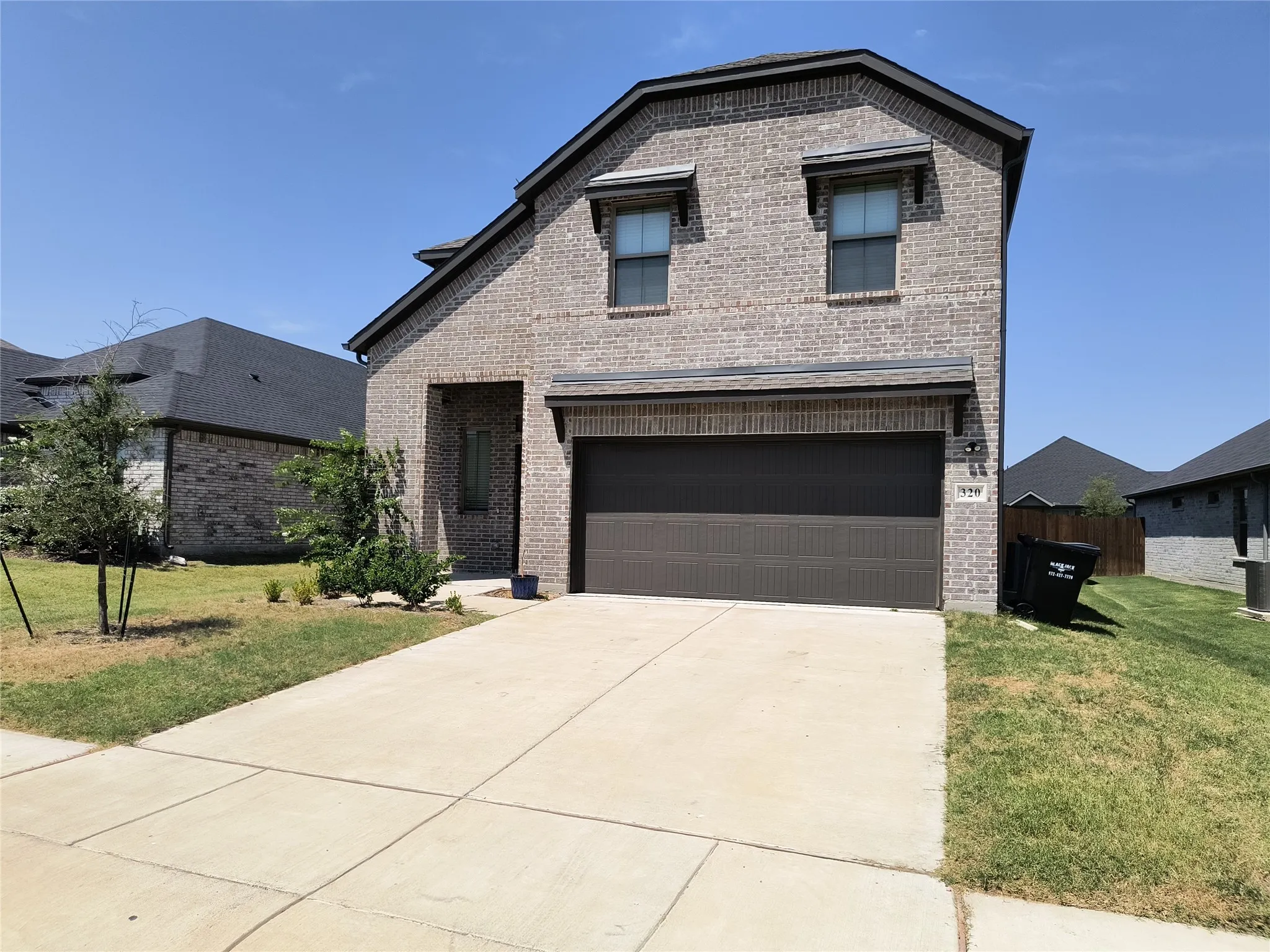 Brick exterior with an attached garage, covered entry, and concrete driveway