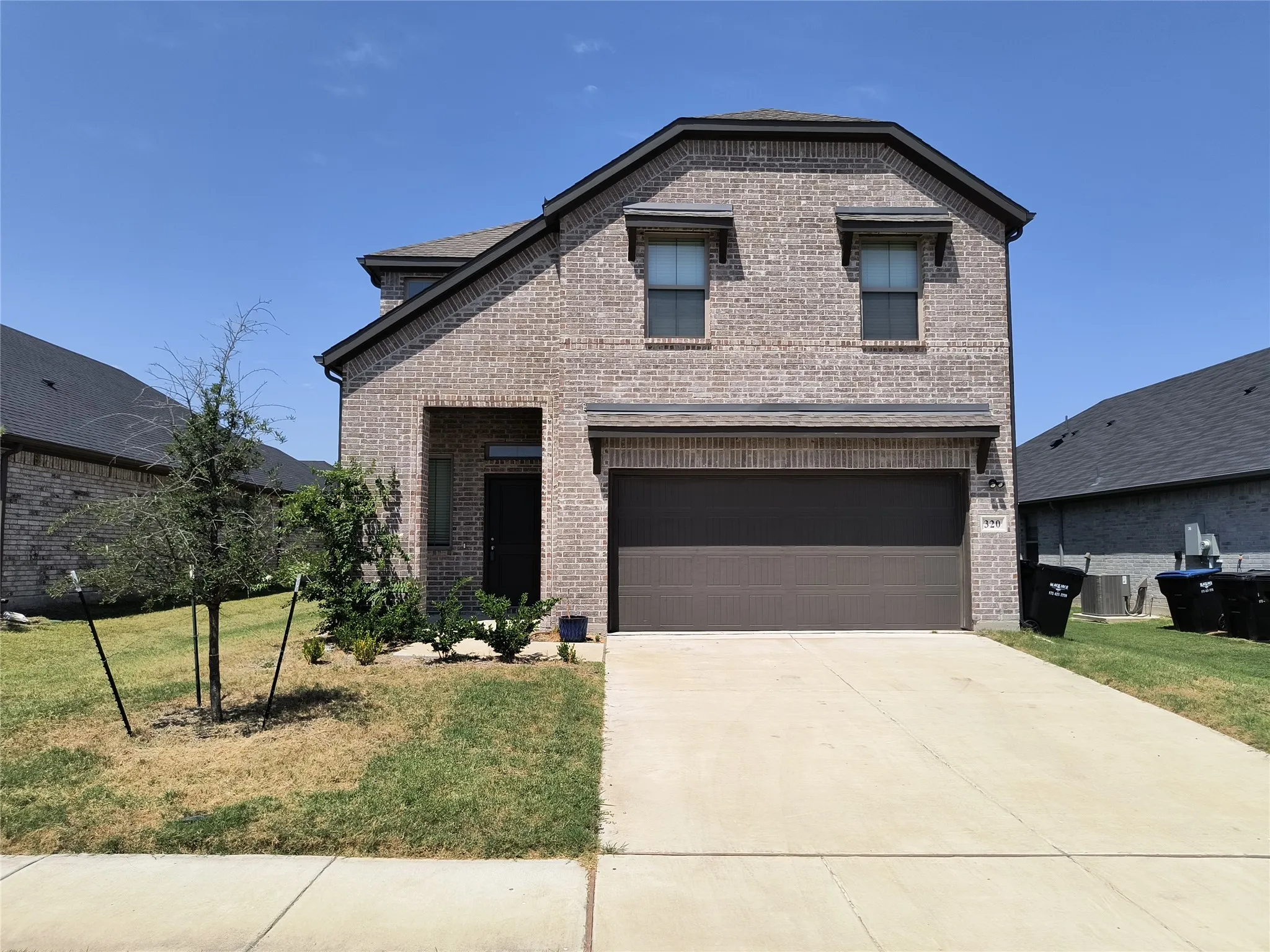 Two-story brick facade, attached garage, concrete driveway, and covered front entry