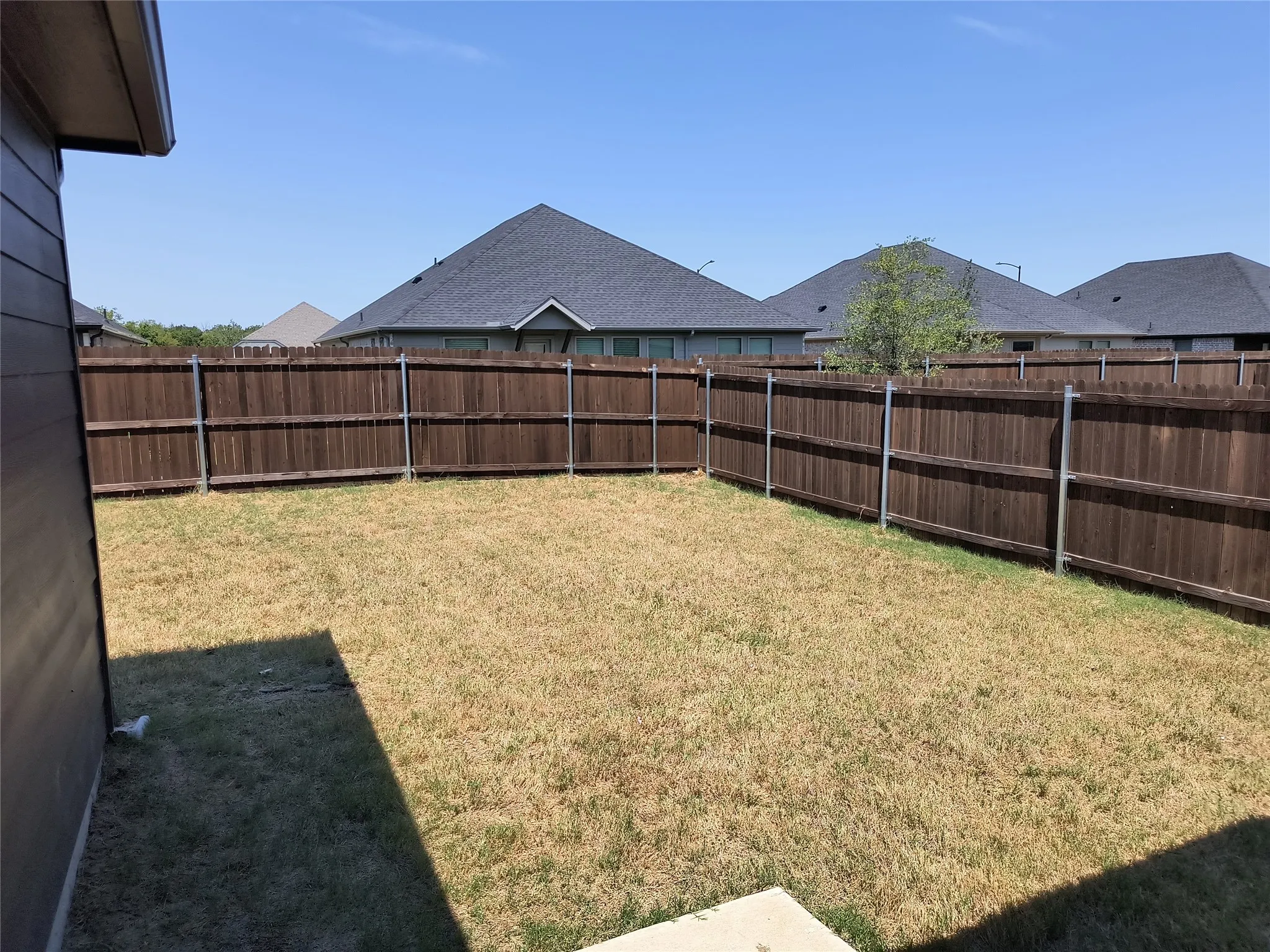 Fenced backyard featuring a wood privacy fence with metal posts
