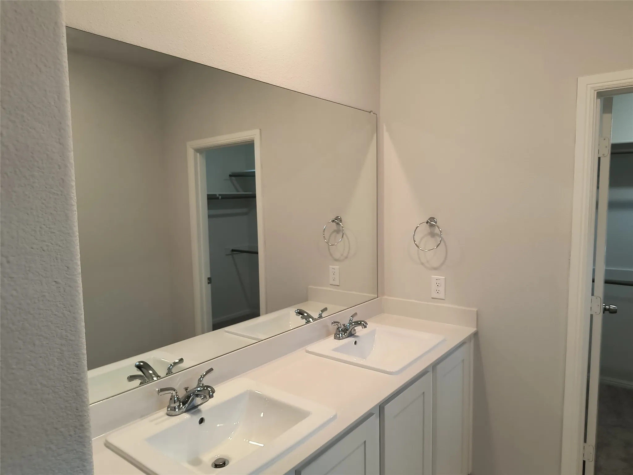 Dual vanity with integrated sinks, chrome fixtures, and a large wall-mounted mirror