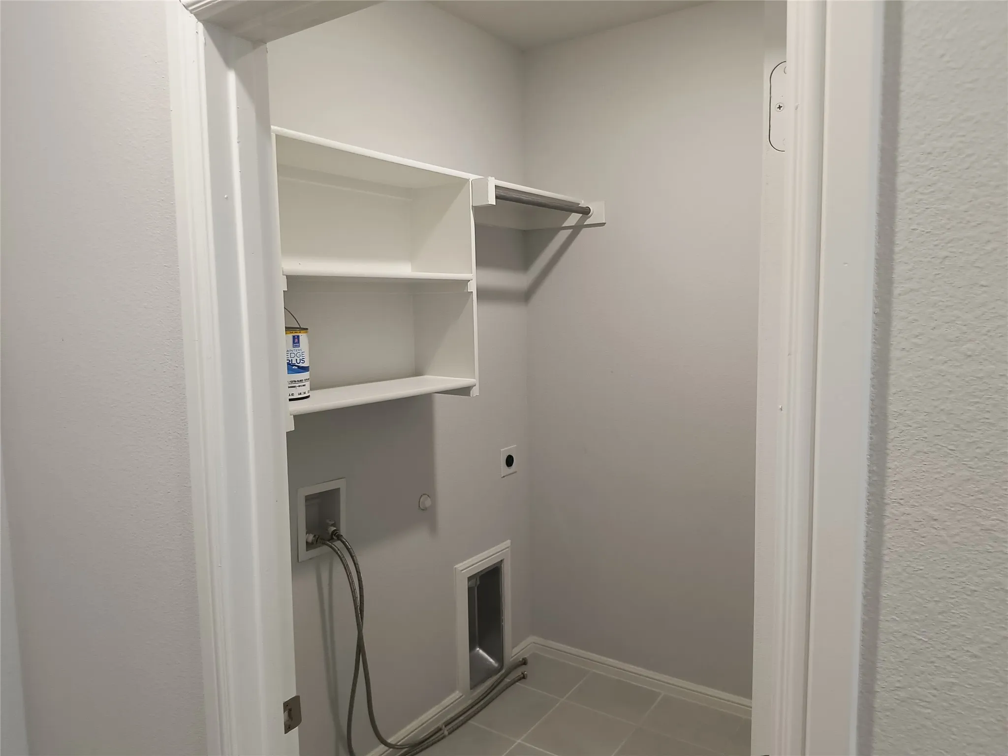 Built-in shelving, hanging rod, and tile flooring