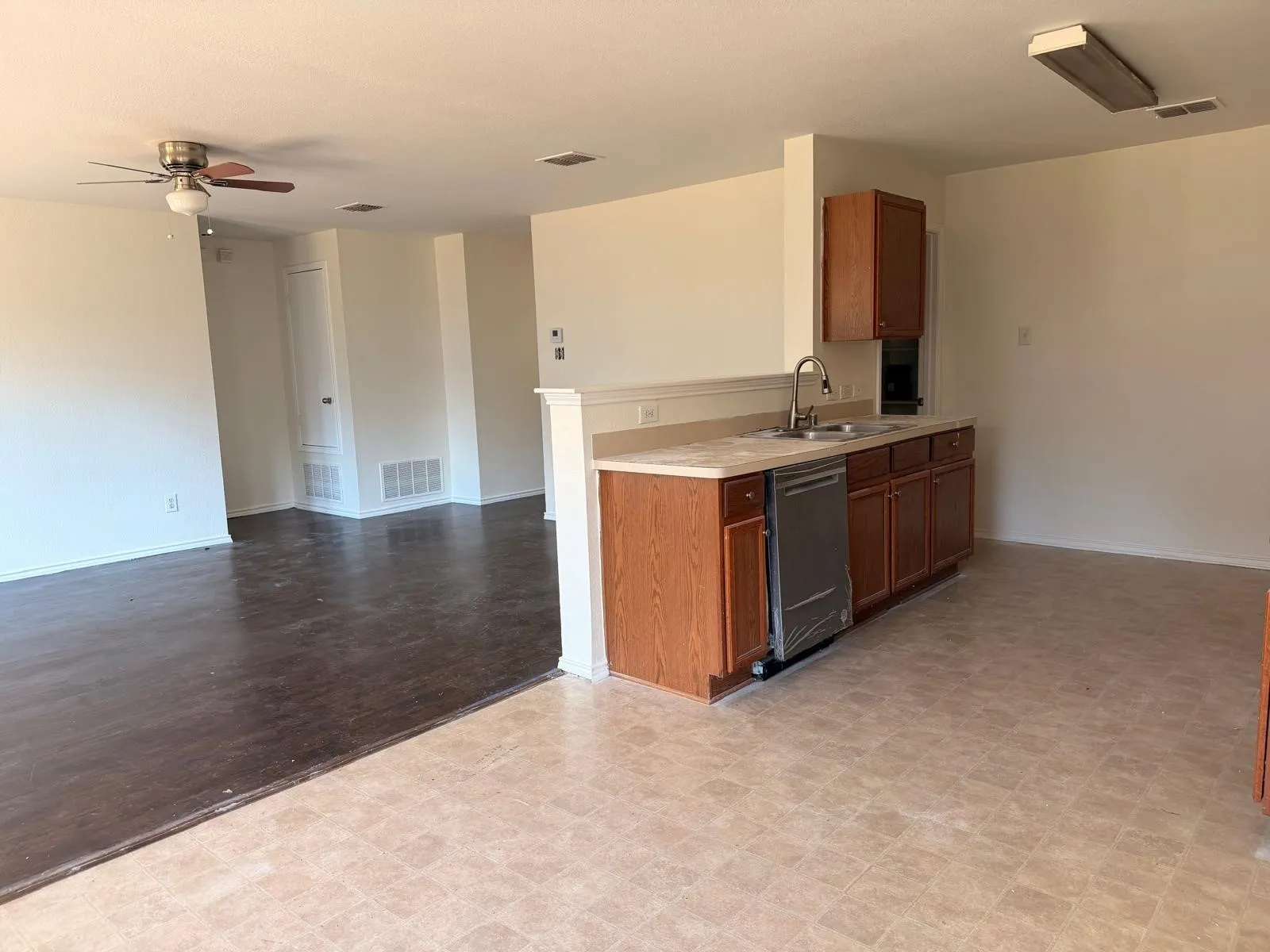 Kitchen featuring wood-finish cabinetry, stainless steel dishwasher, and a dual-basin sink with a gooseneck faucet