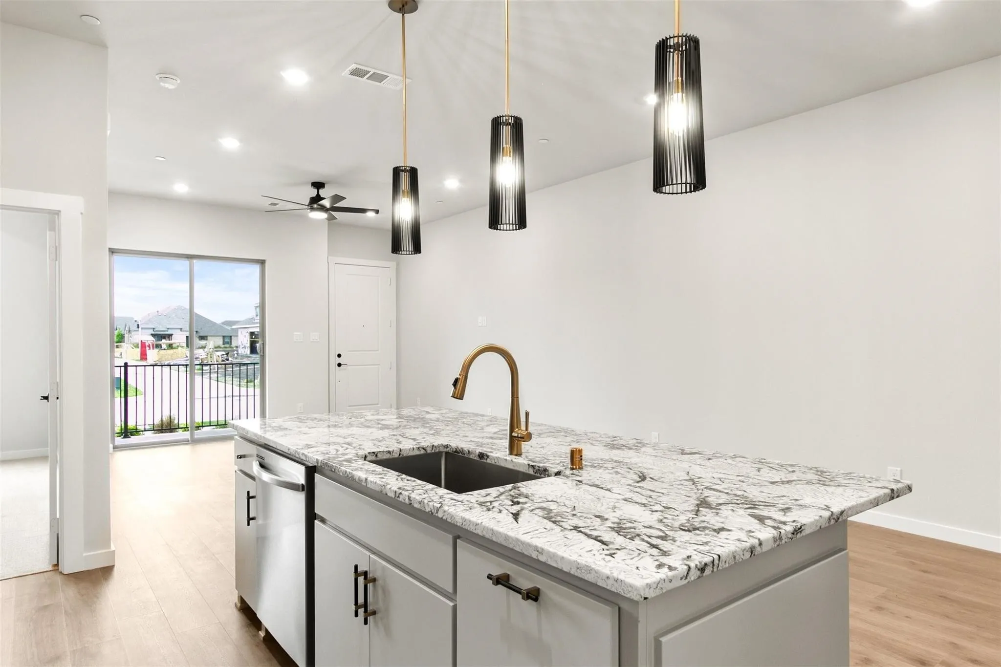 Kitchen featuring an island with sink, ceiling fan, light wood-style flooring, decorative light fixtures, and recessed lighting