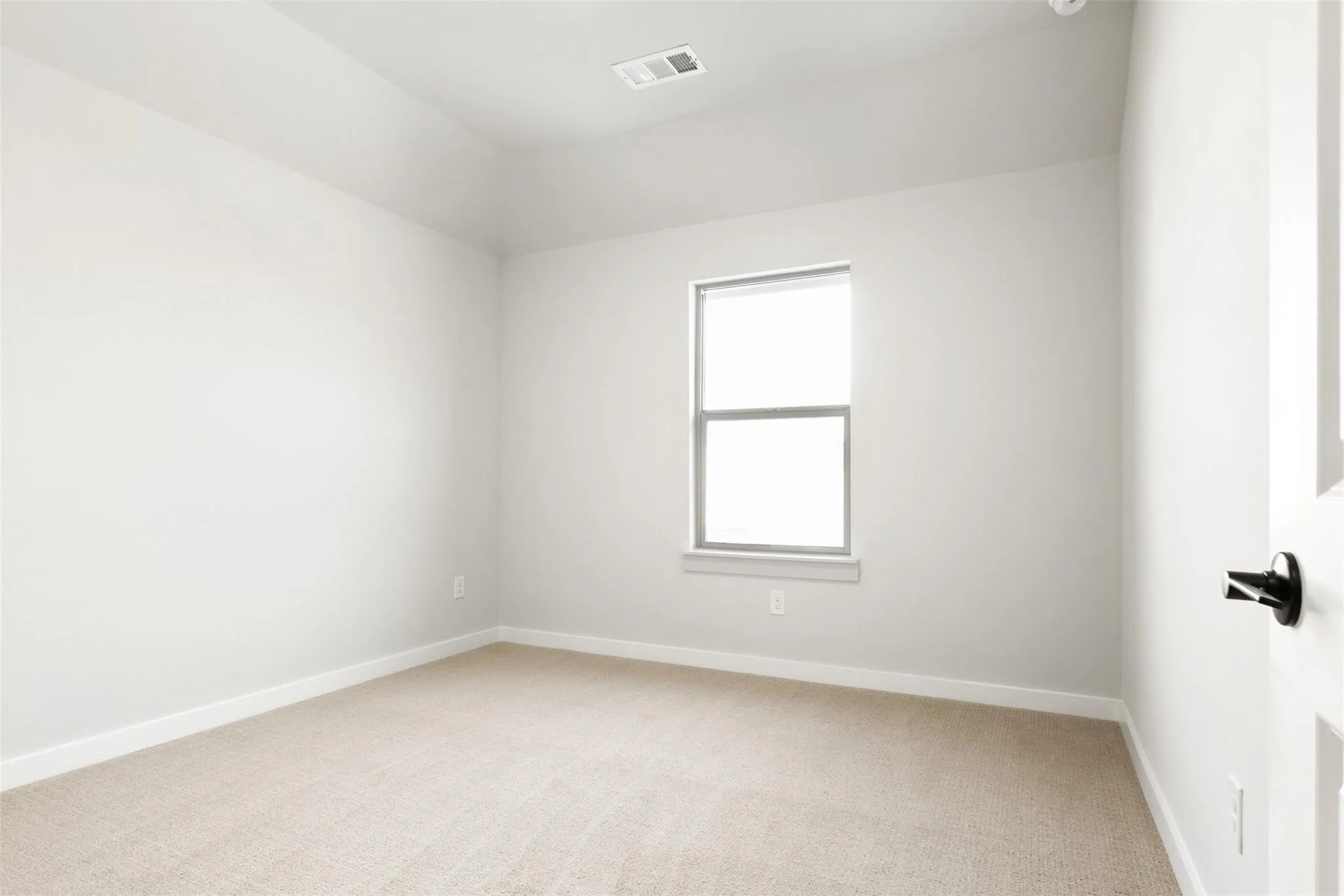 Empty room with light colored carpet and baseboards