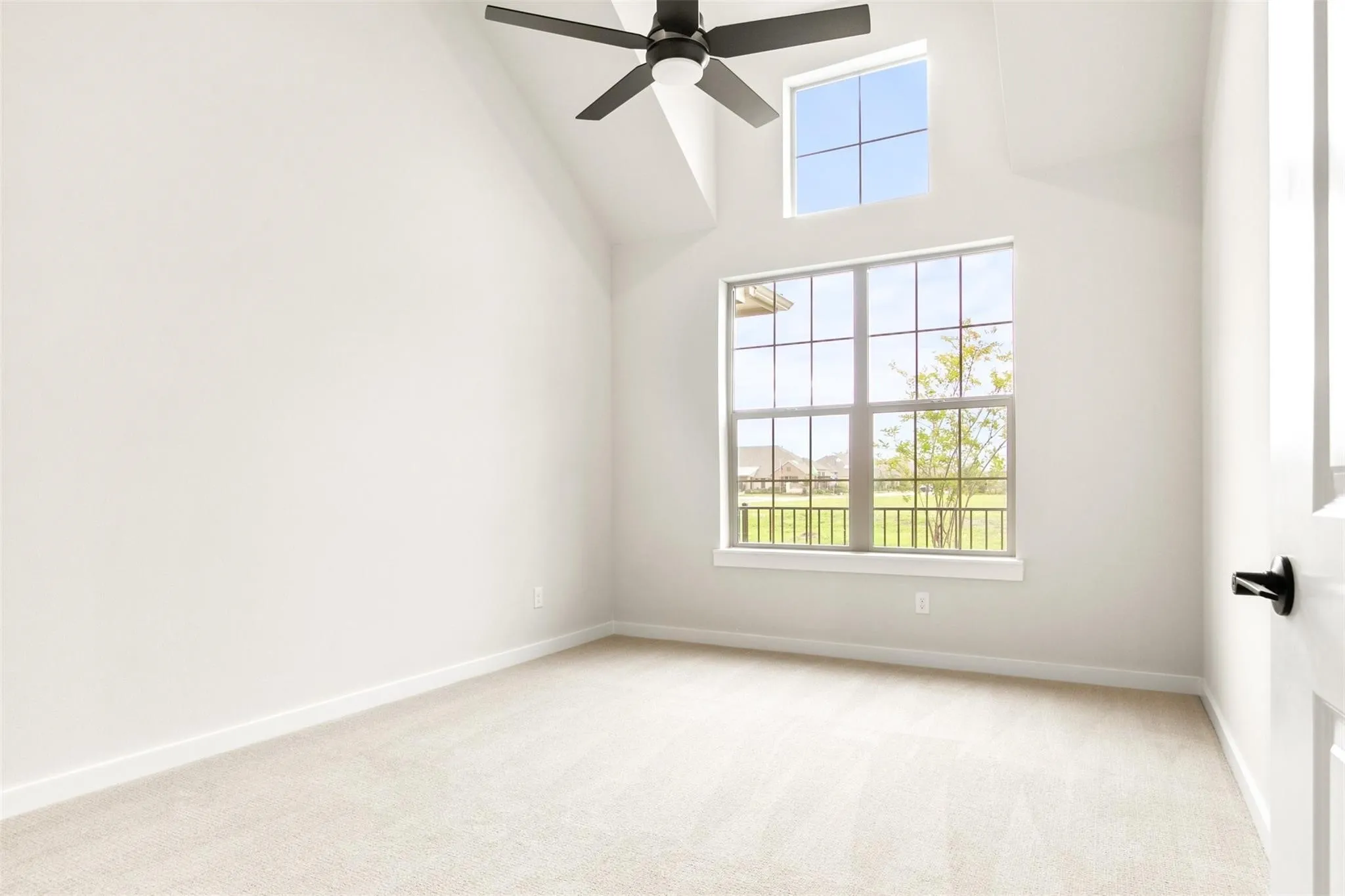 Spare room with ceiling fan, light colored carpet, healthy amount of natural light, and a towering ceiling