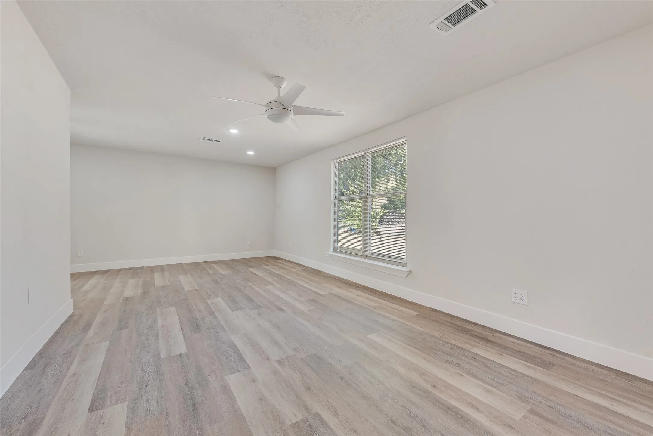 Recessed lighting, ceiling fan, large window, wood-finish flooring, and white walls