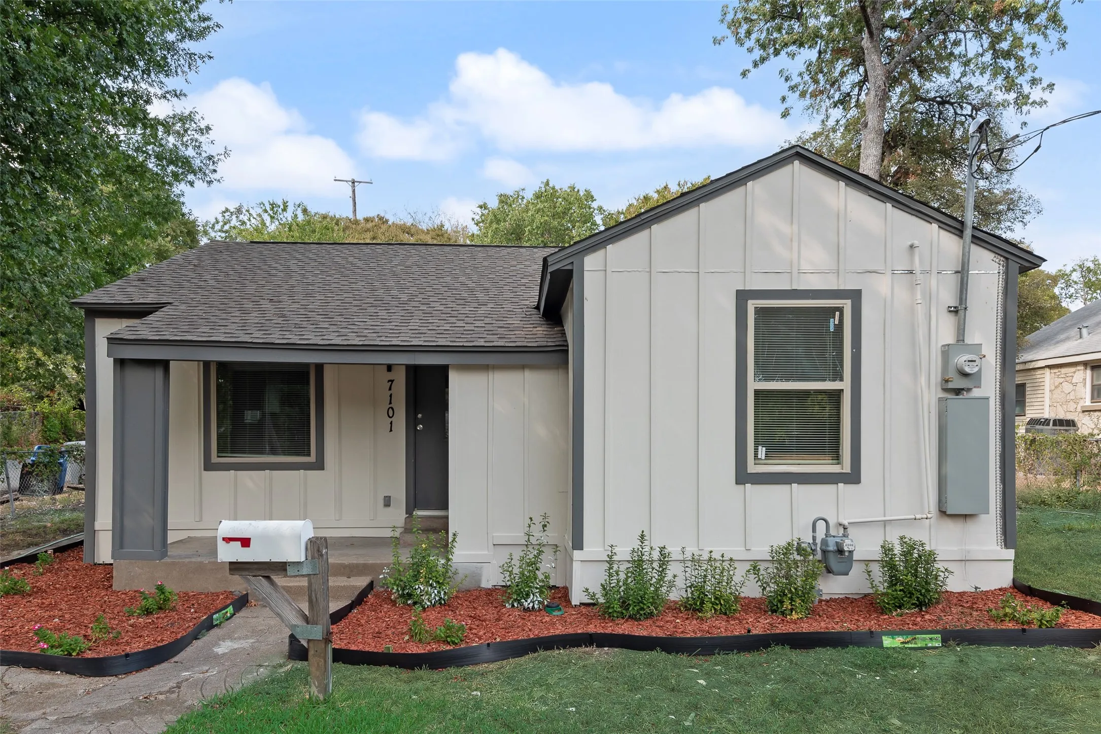 Neutral-toned exterior with dark trim accents, covered entry, and pitched shingle roof