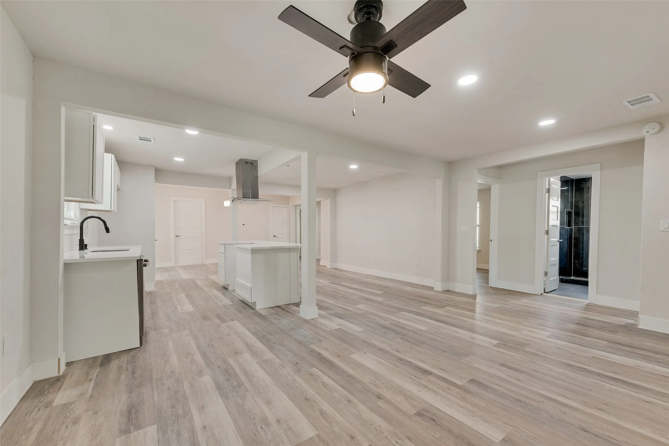 Open-concept living area with wood-finish flooring, recessed lighting, and a ceiling fan
