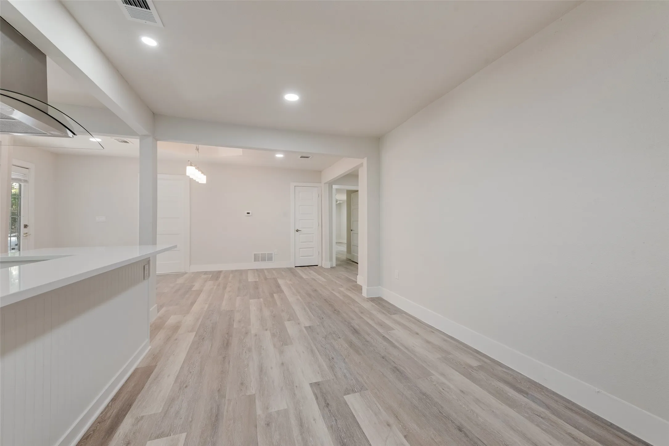 Open concept layout with wood-finish flooring, recessed lighting, and a kitchen island featuring a light-toned countertop