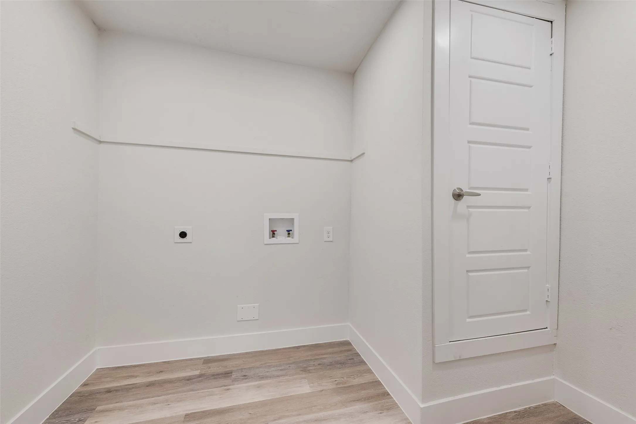 Utility room featuring wood-finish flooring, white walls, and a five-panel interior door
