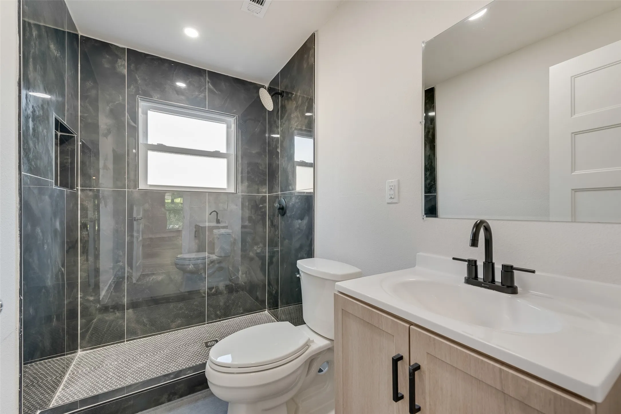 Shower featuring dark tile surround and recessed shelf
