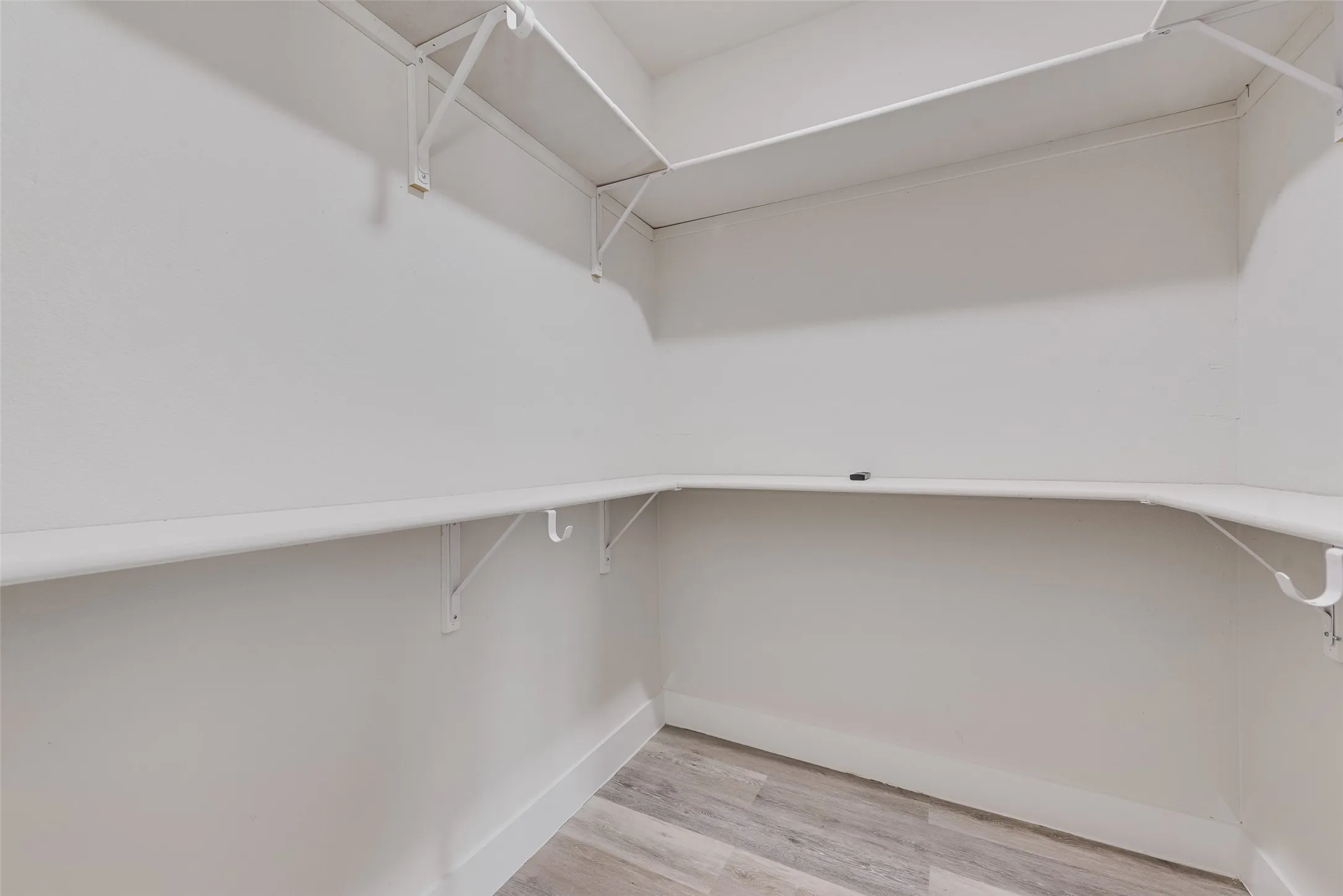 Built-in shelving system with hanging rods and wood-finish flooring