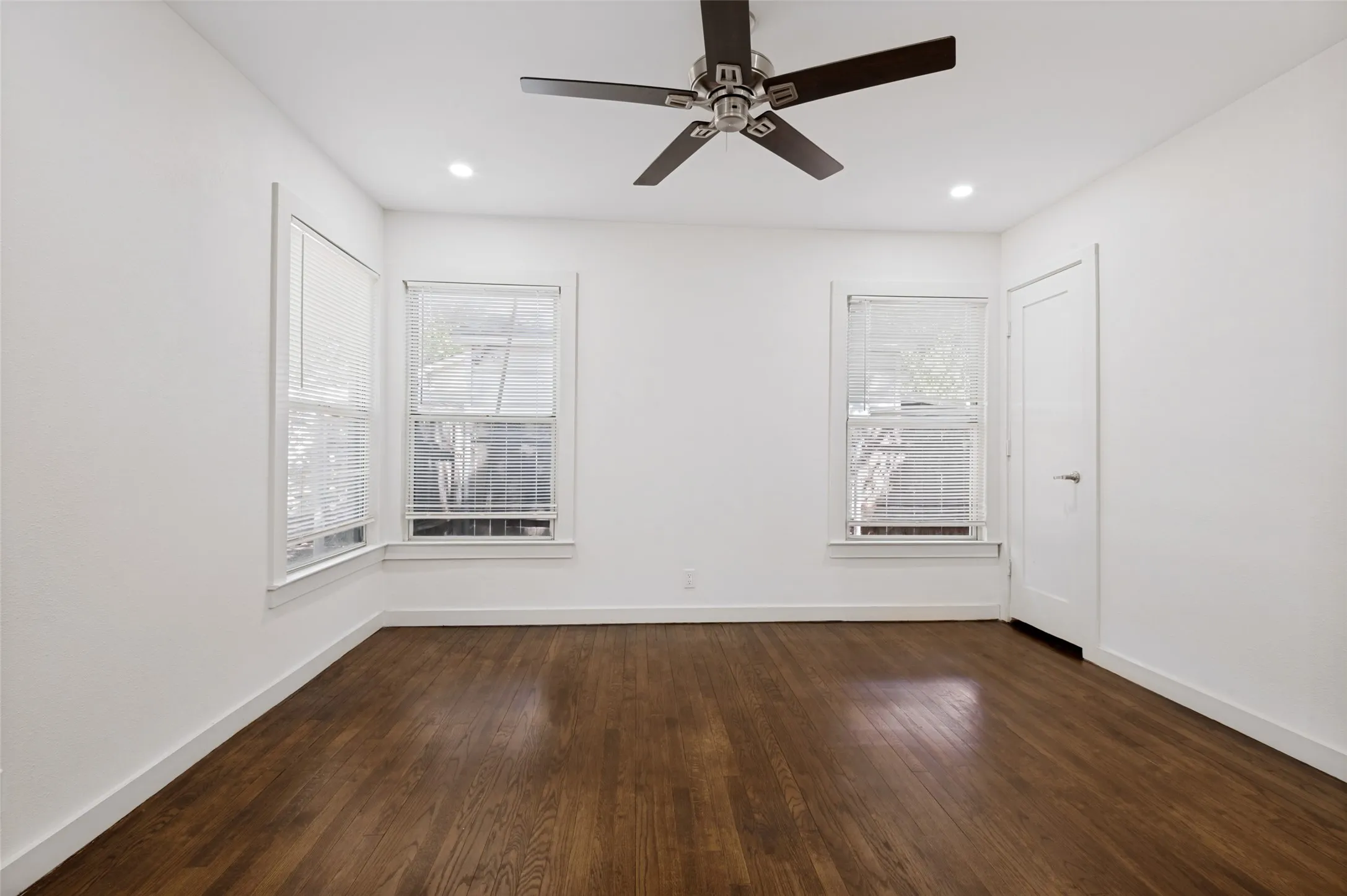 Rich wood-finish flooring, recessed lighting, and a ceiling fan