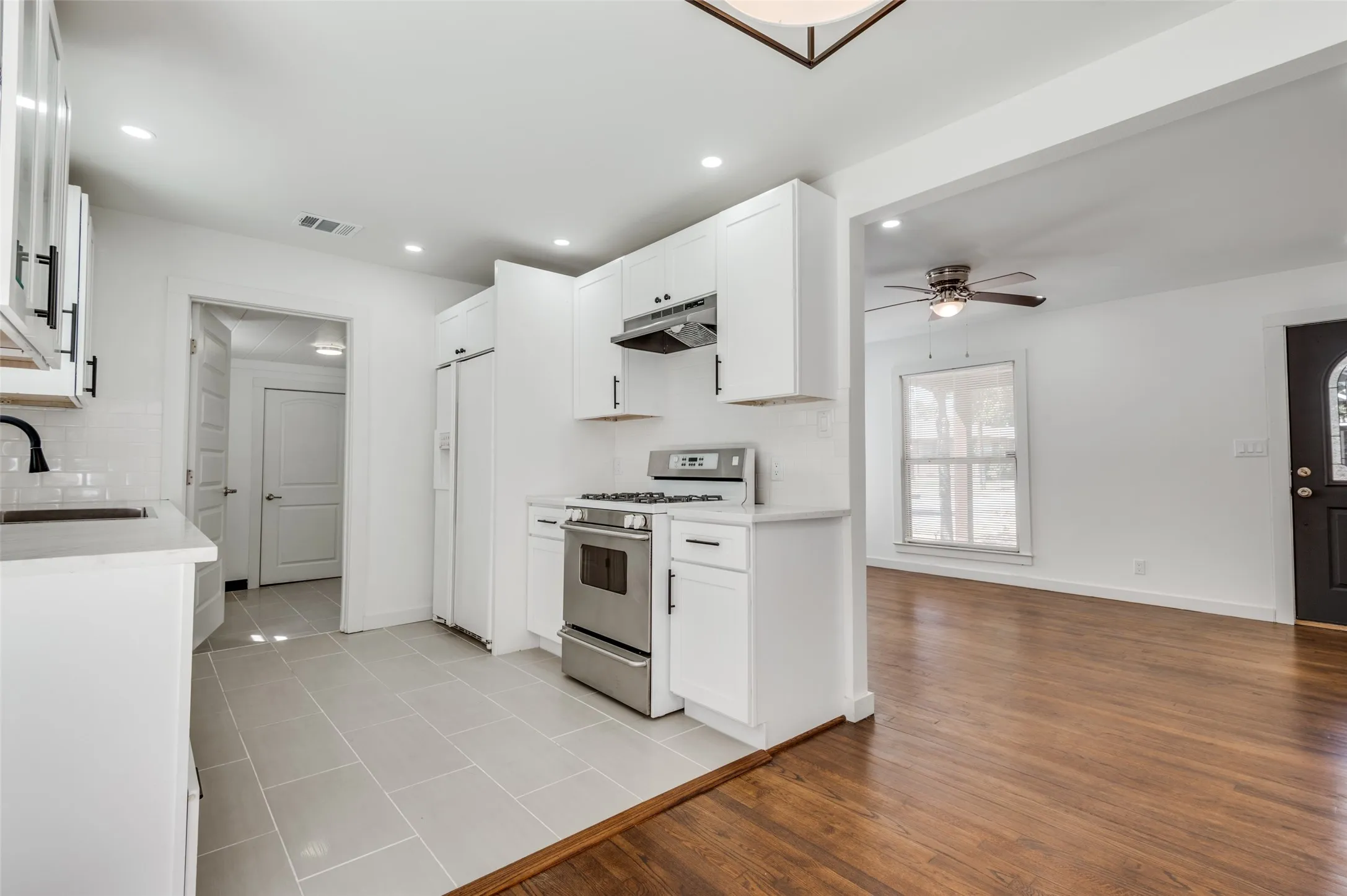 Kitchen featuring white cabinetry, stainless steel appliances, light-toned tile flooring, and white countertops