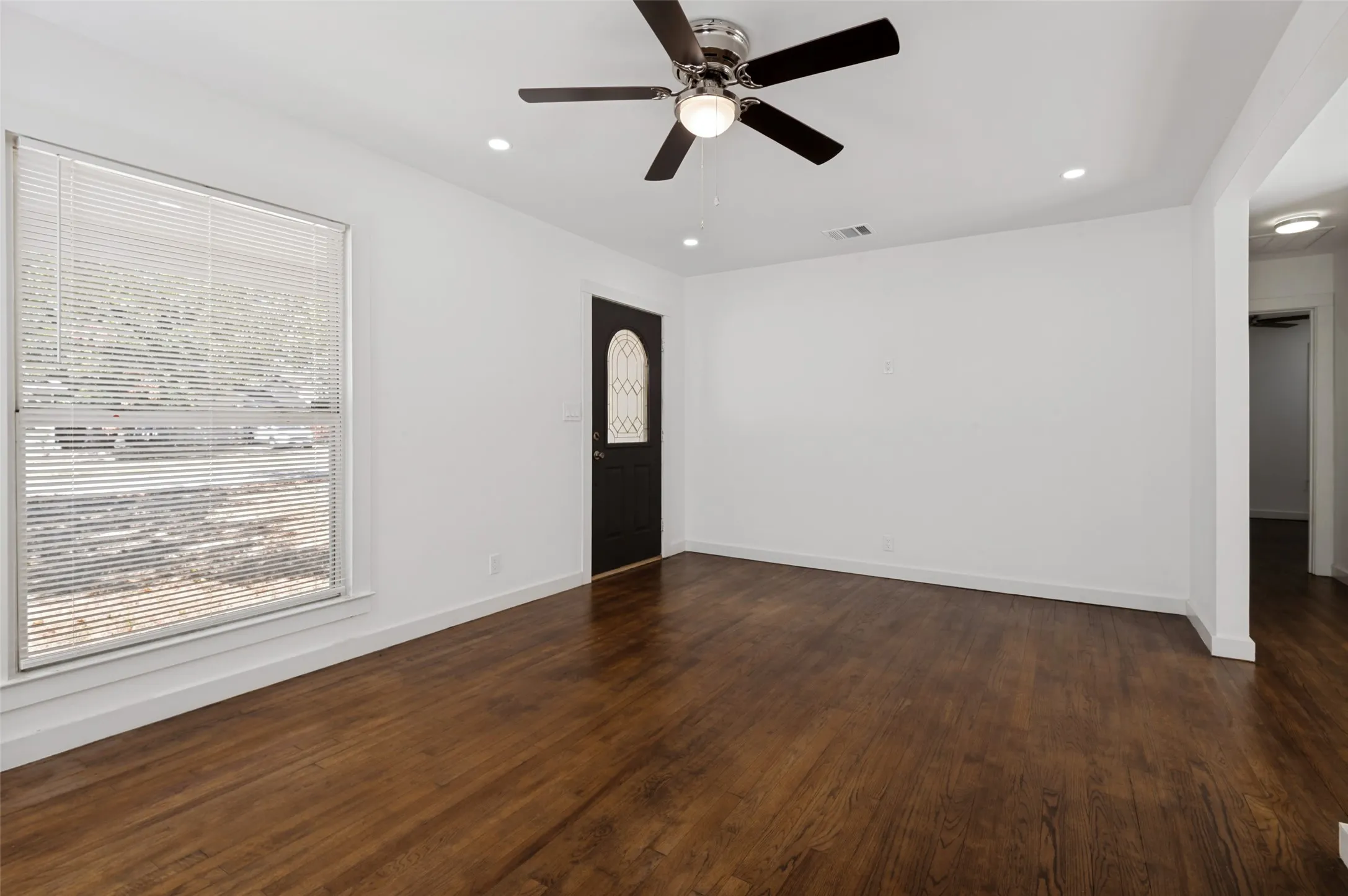 Wood-finish flooring throughout, complemented by recessed lighting and a ceiling fan with integrated illumination