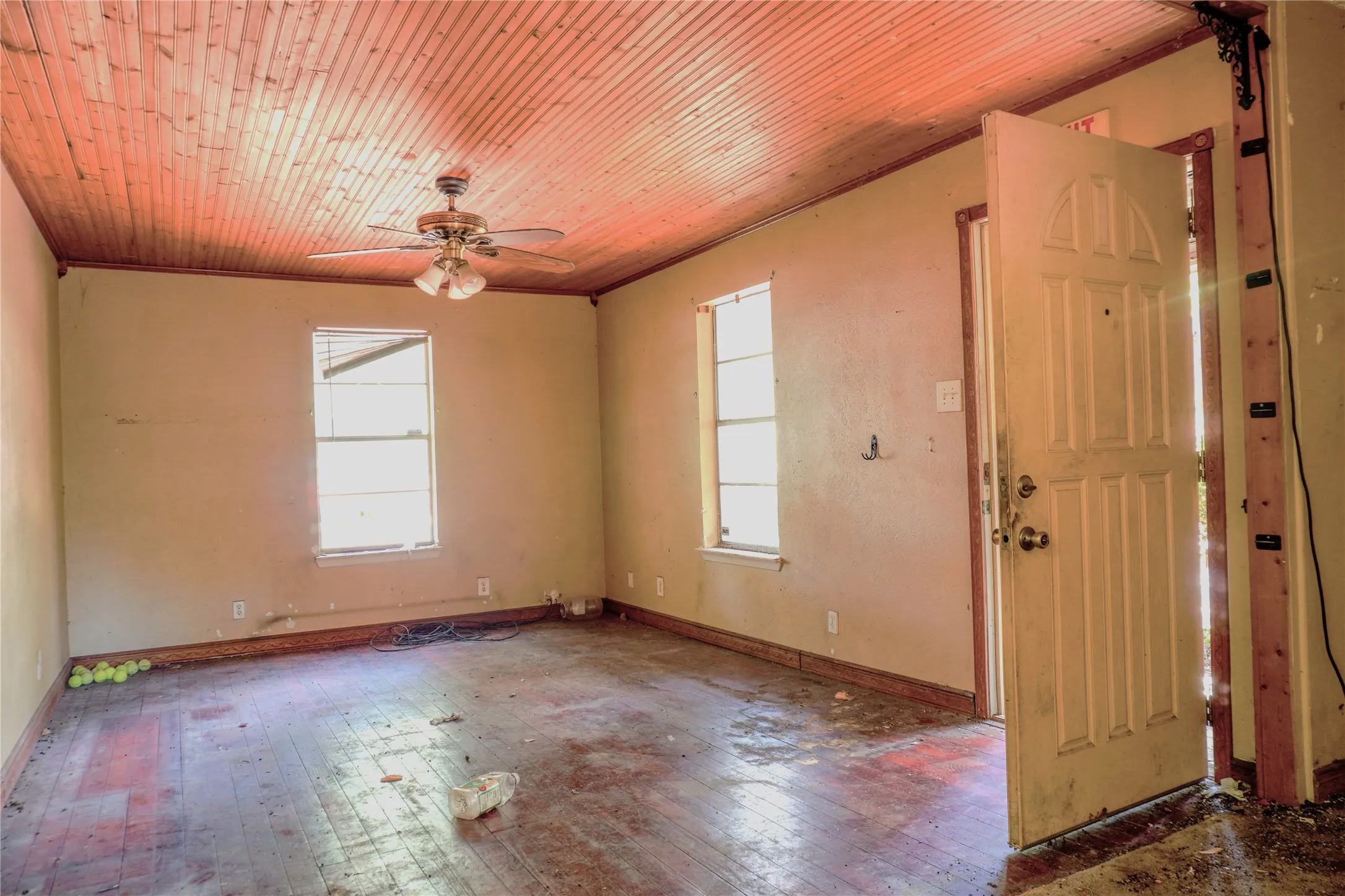Wood-plank ceiling, wood-finish flooring, two windows, ceiling fan with light fixture, and a paneled entry door