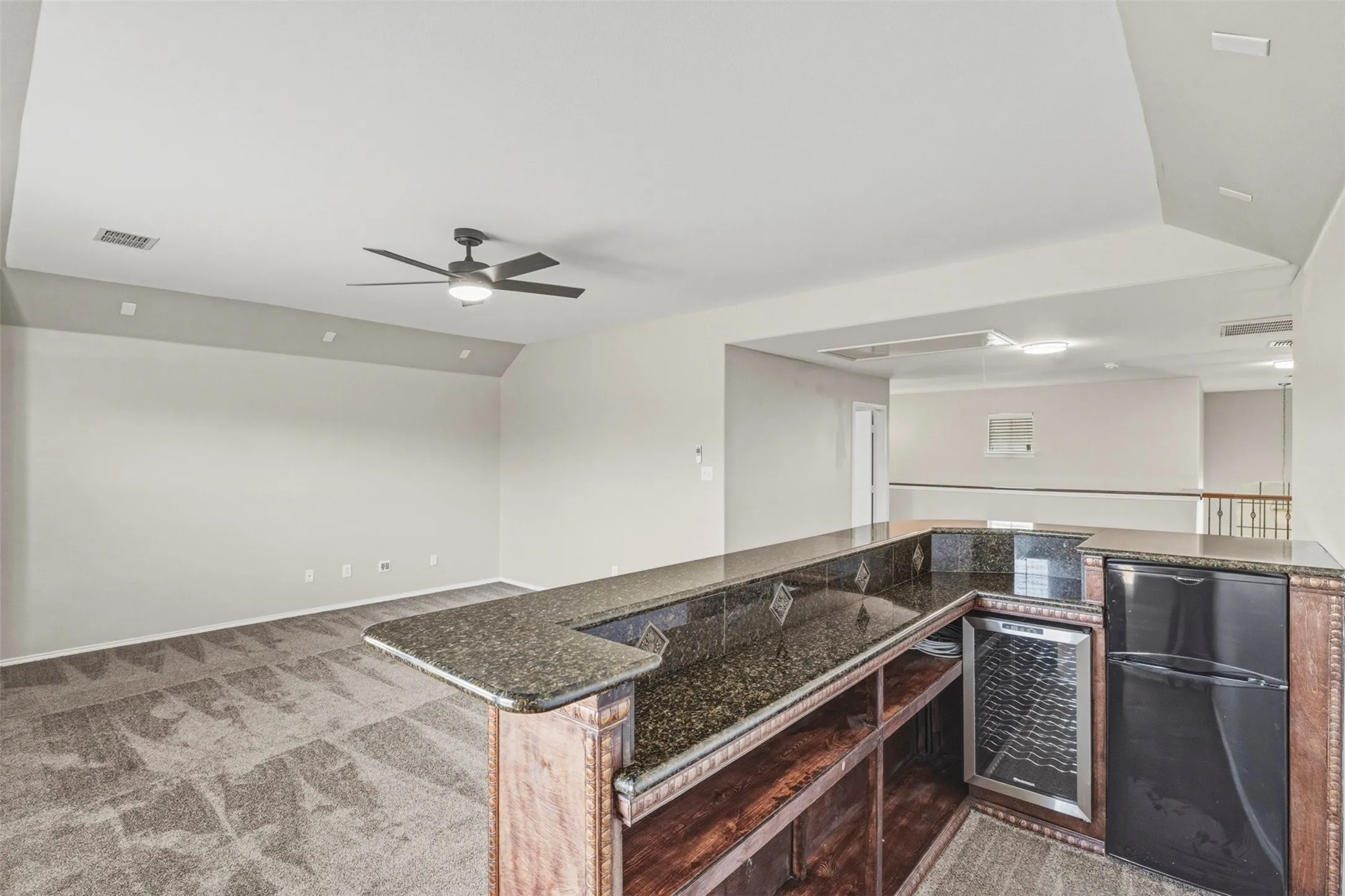 Wet bar featuring dark countertops, built-in beverage cooler, and refrigerator